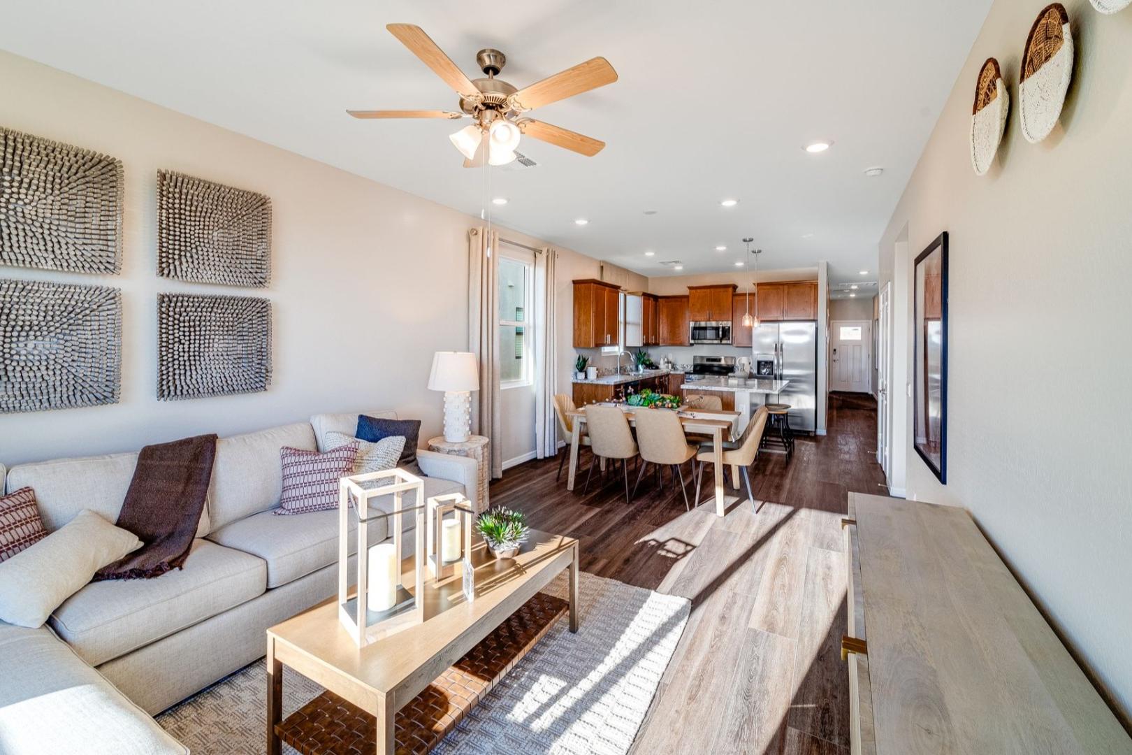 Open-concept living and dining area in The Savannah B with beige sofa, wooden table, oak kitchen cabinets, and hardwood floors
