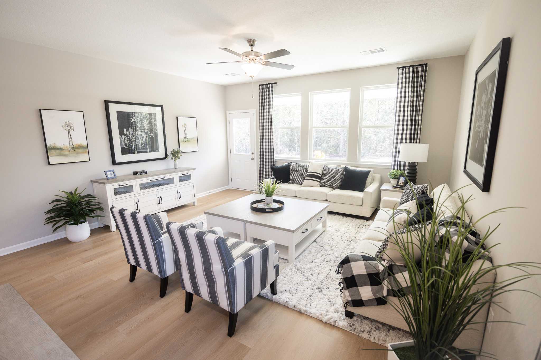 Open-concept living room at Silver Oak in Cusseta Alabama with neutral tones hardwood floors white sofa blue armchairs and potted plants