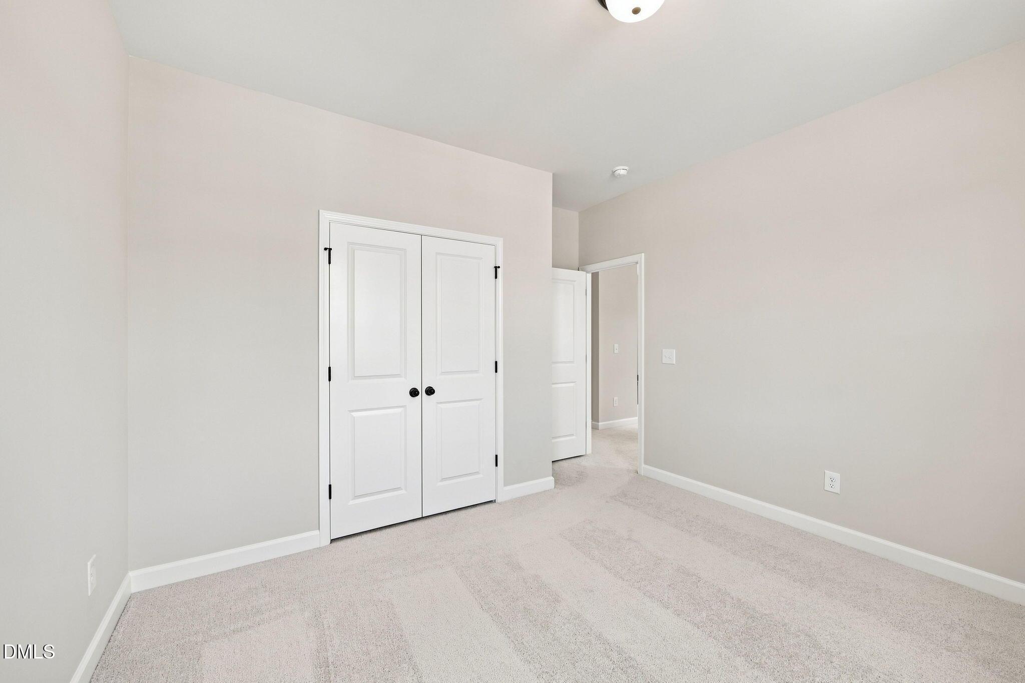 Bright secondary bedroom with carpet and double-door closet in The Harris C floor plan, Forestville Yard, Knightdale, NC.