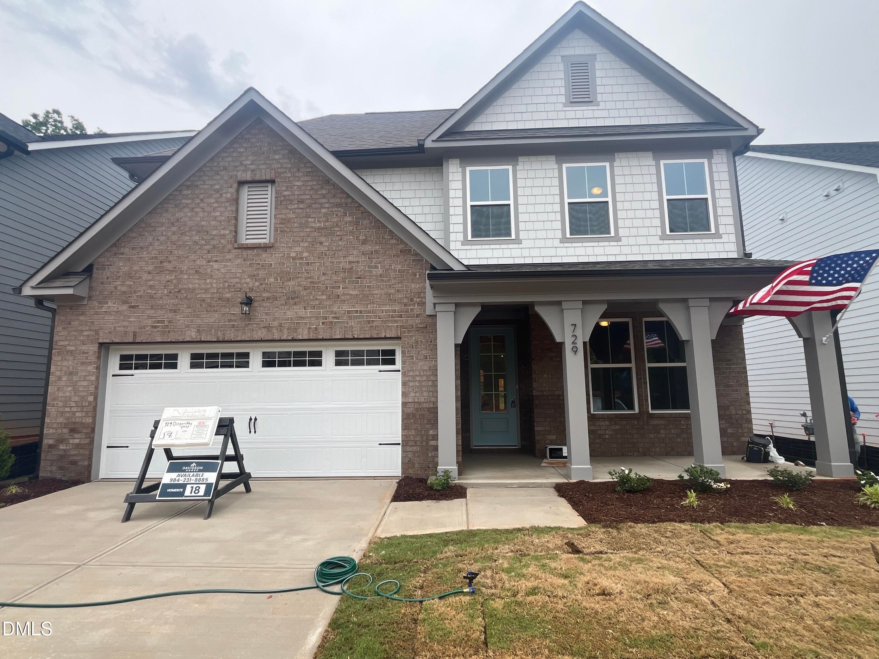 Modern two-story brick home with two-car garage, covered porch, and American flag in Sage on North Main, Wake Forest, NC by Davidson Homes
