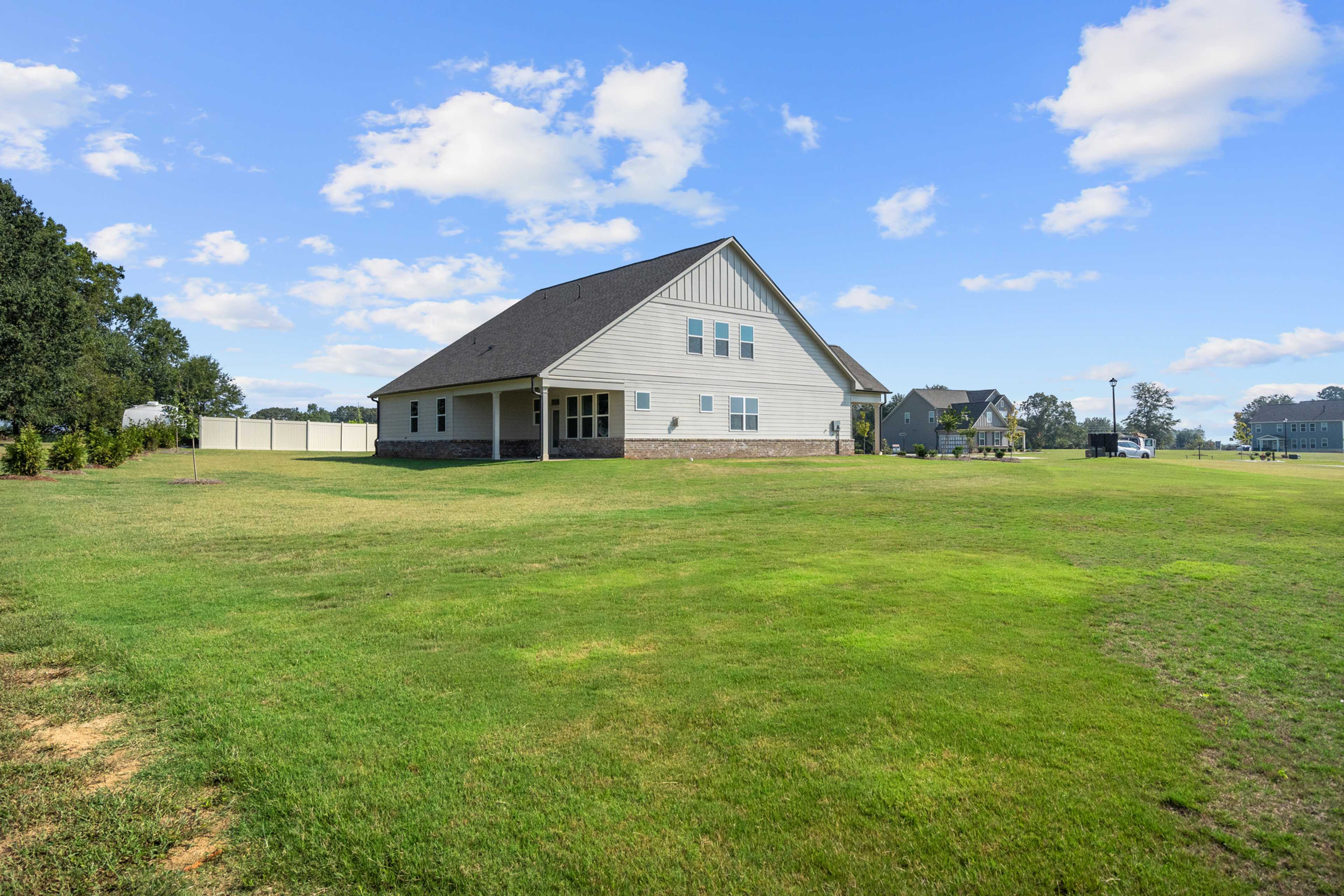 Modern white farmhouse-style home exterior at Everleigh in Locust Grove, GA with gabled roof, side porch, and lush green lawn