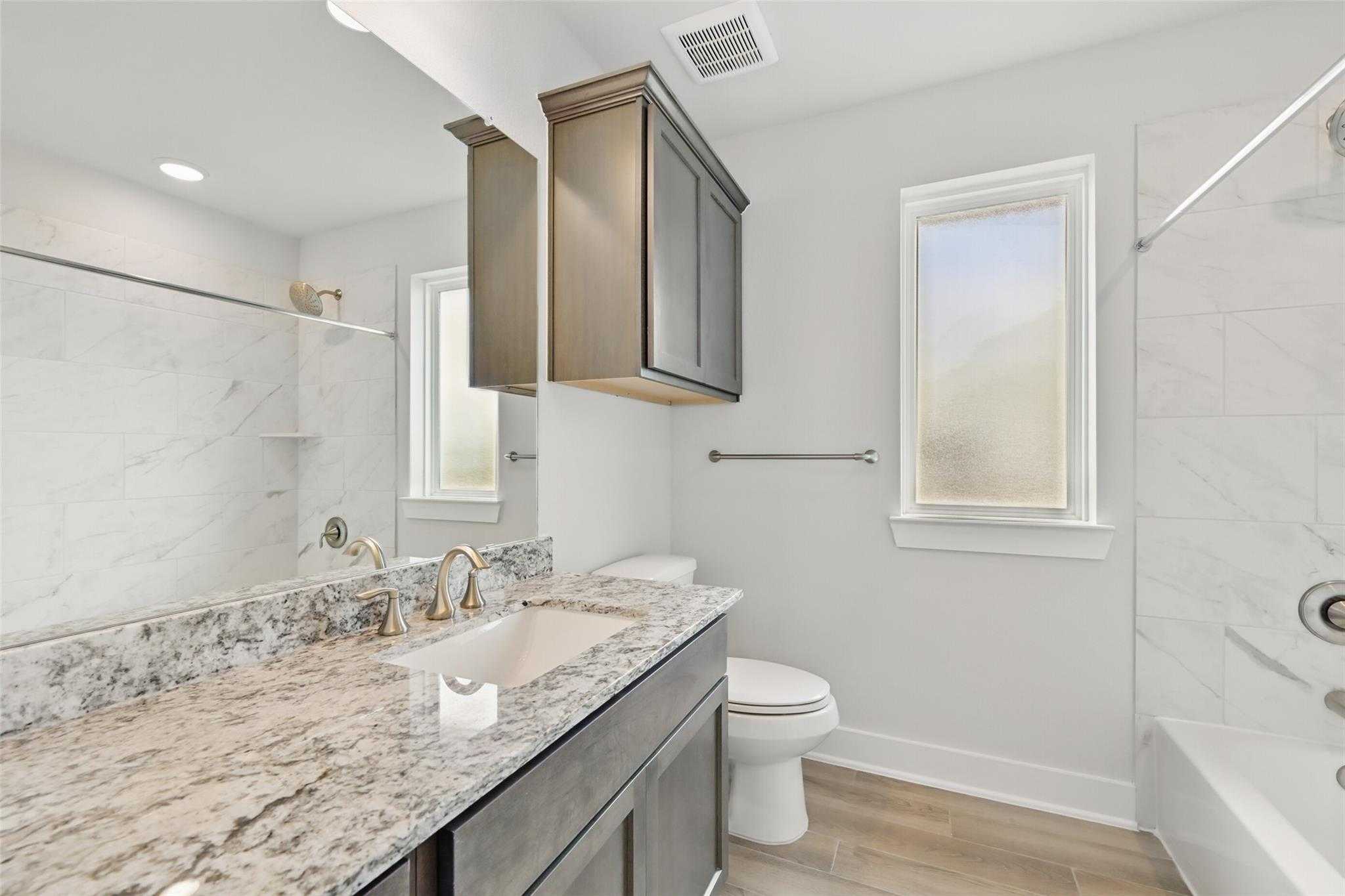 Modern bathroom featuring white subway tile, quartz vanity with gray cabinets, and tub-shower combo in Davidson Homes The Philip A, Lago Mar, Texas City