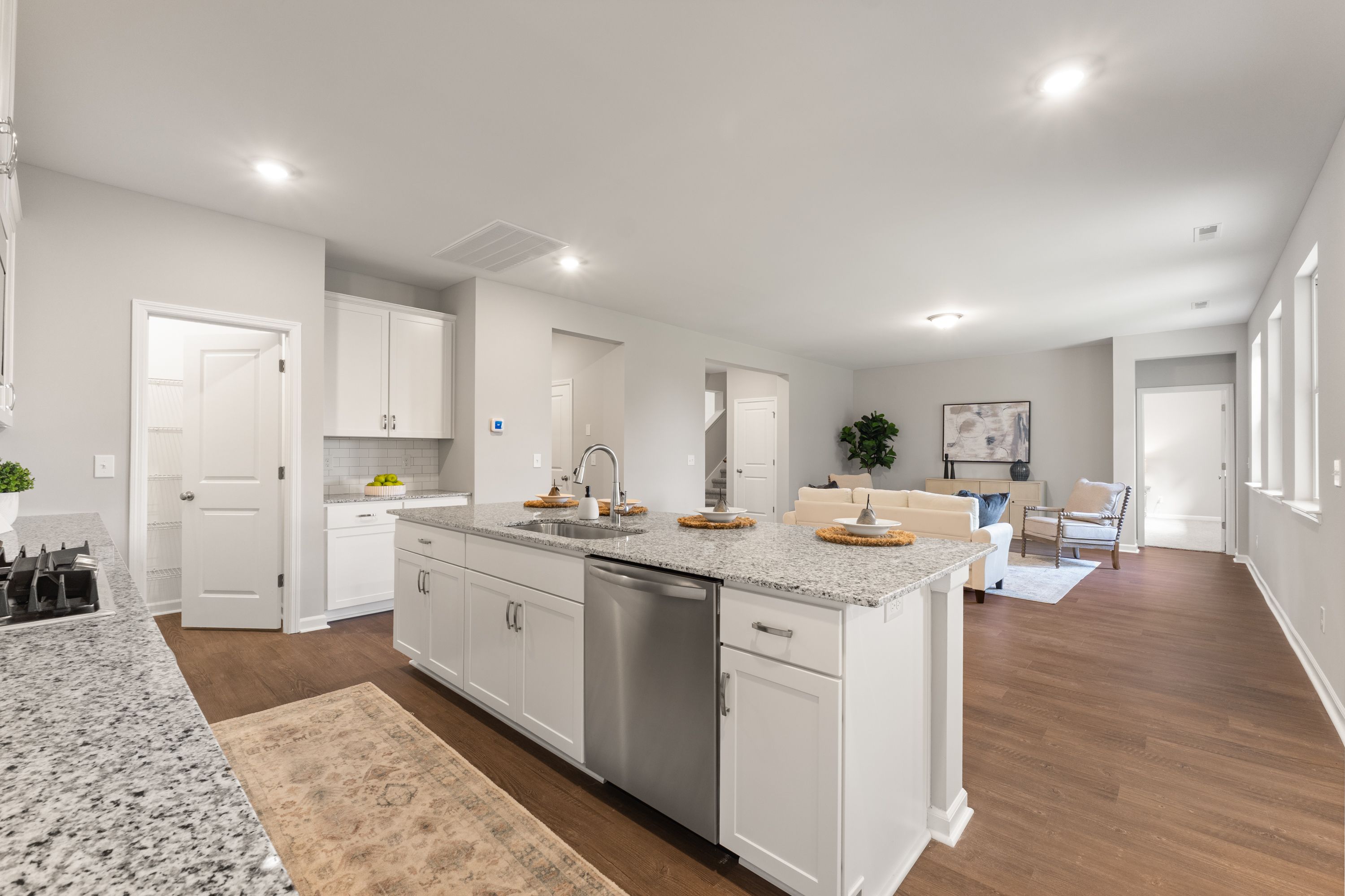 Spacious open-concept kitchen in The Avalon E with white shaker cabinets, quartz island, stainless appliances, and adjacent living area