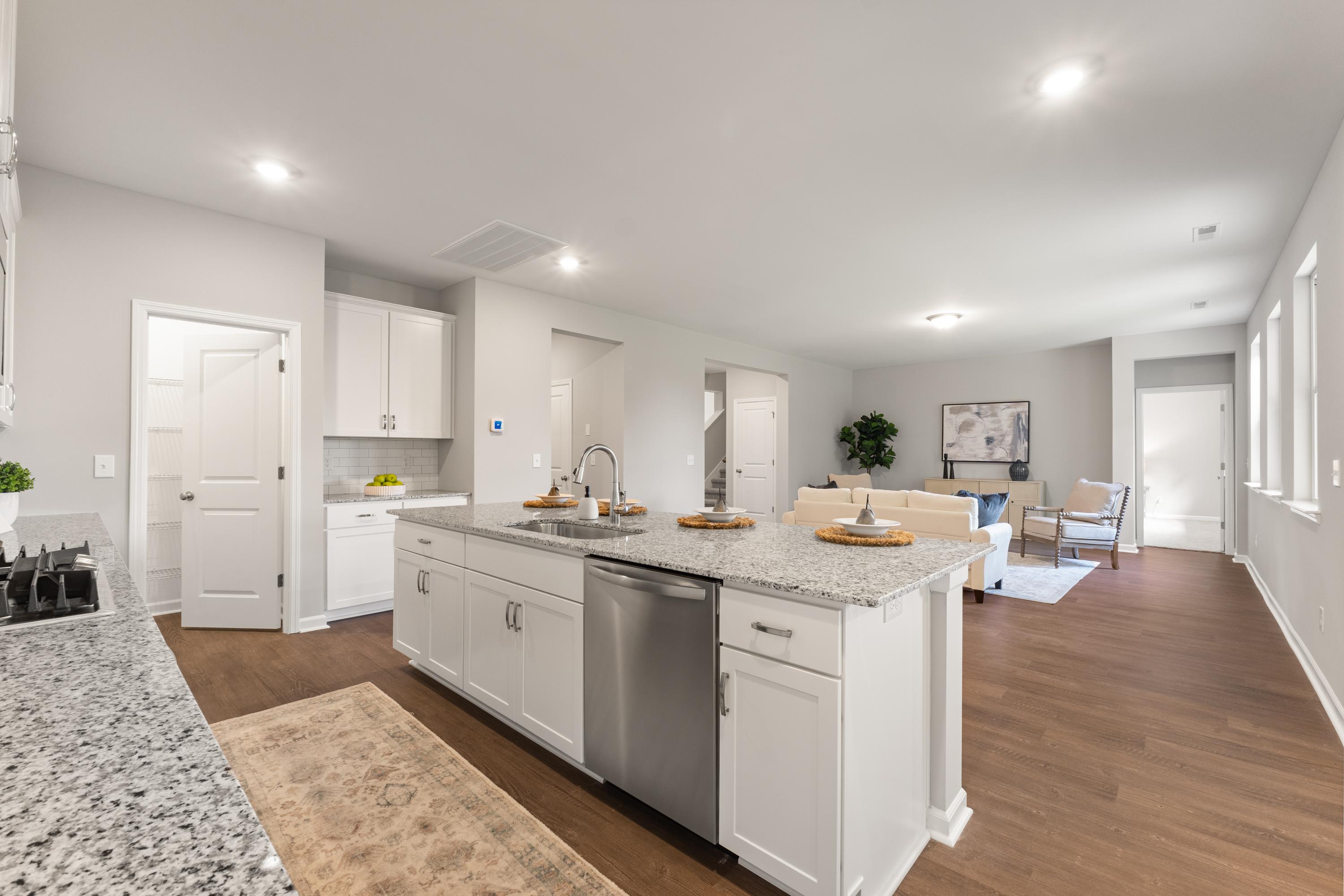 Spacious open-concept kitchen and living area in The Avalon D featuring white shaker cabinets, quartz island, stainless appliances, hardwood floors