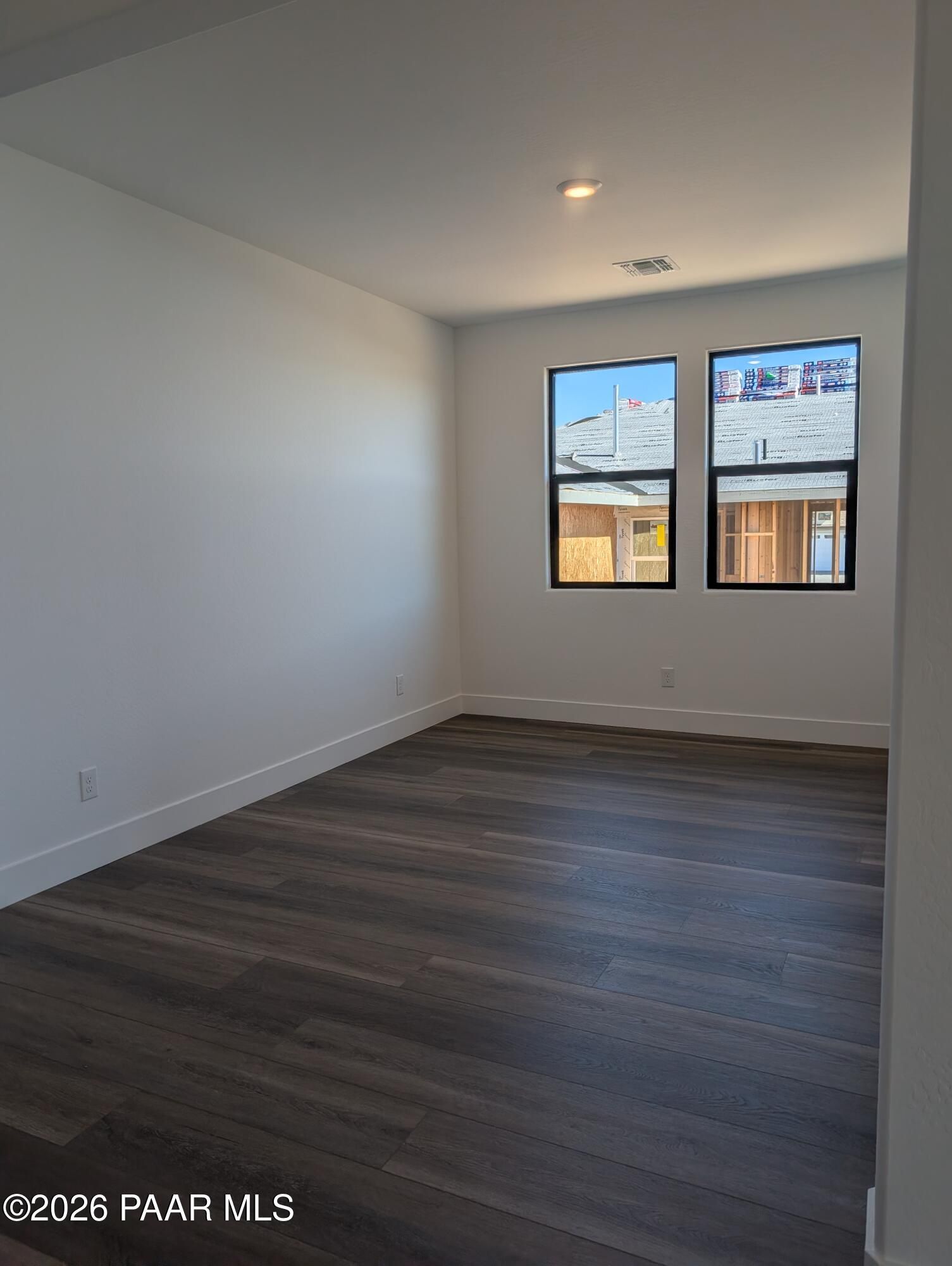 Bright empty room with large black-framed windows and luxury vinyl plank flooring in The Sheridan II G, Prescott, Arizona