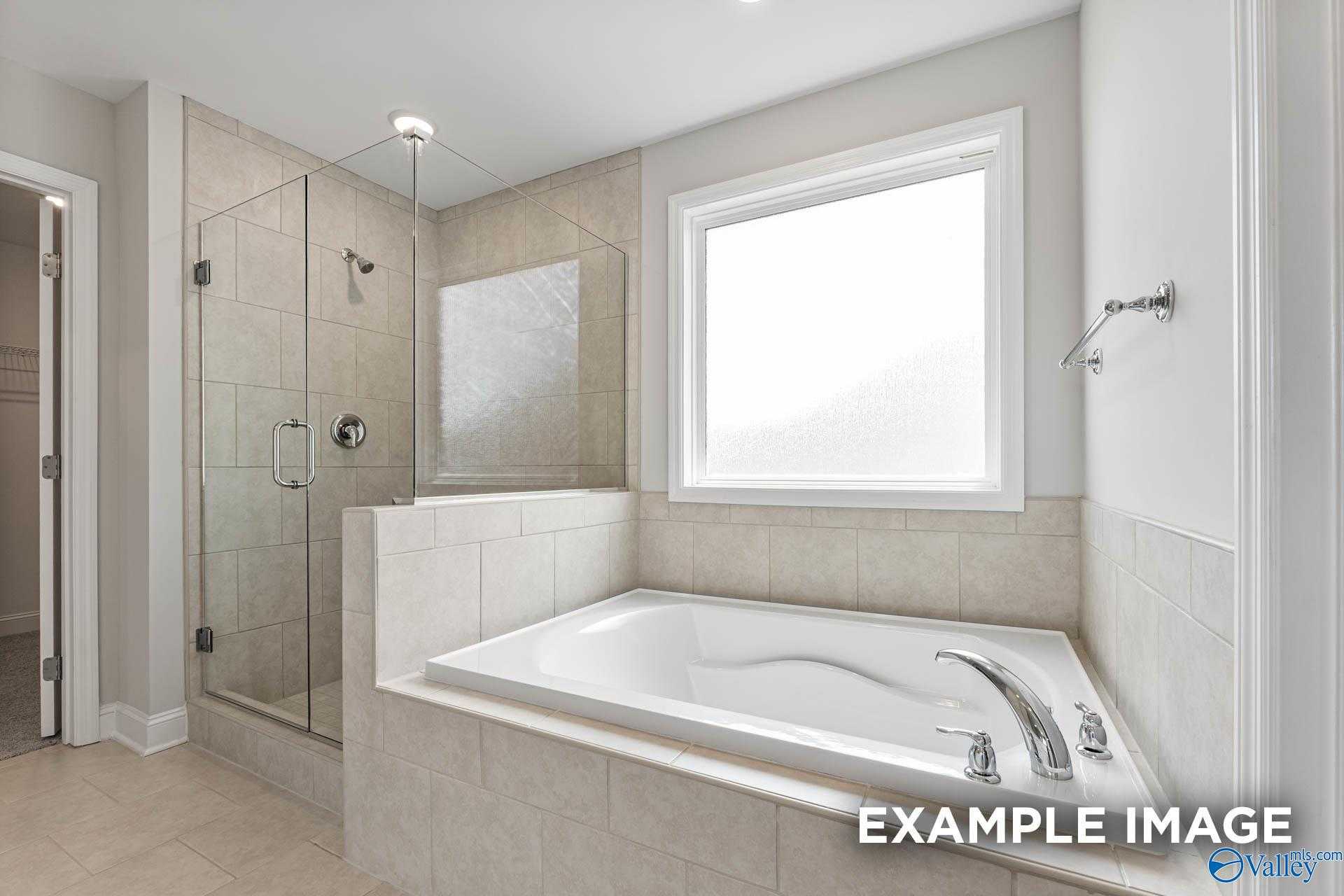 Modern master bathroom featuring frameless glass shower and corner soaking tub in Davidson Homes The Madison A, Harvest, Alabama