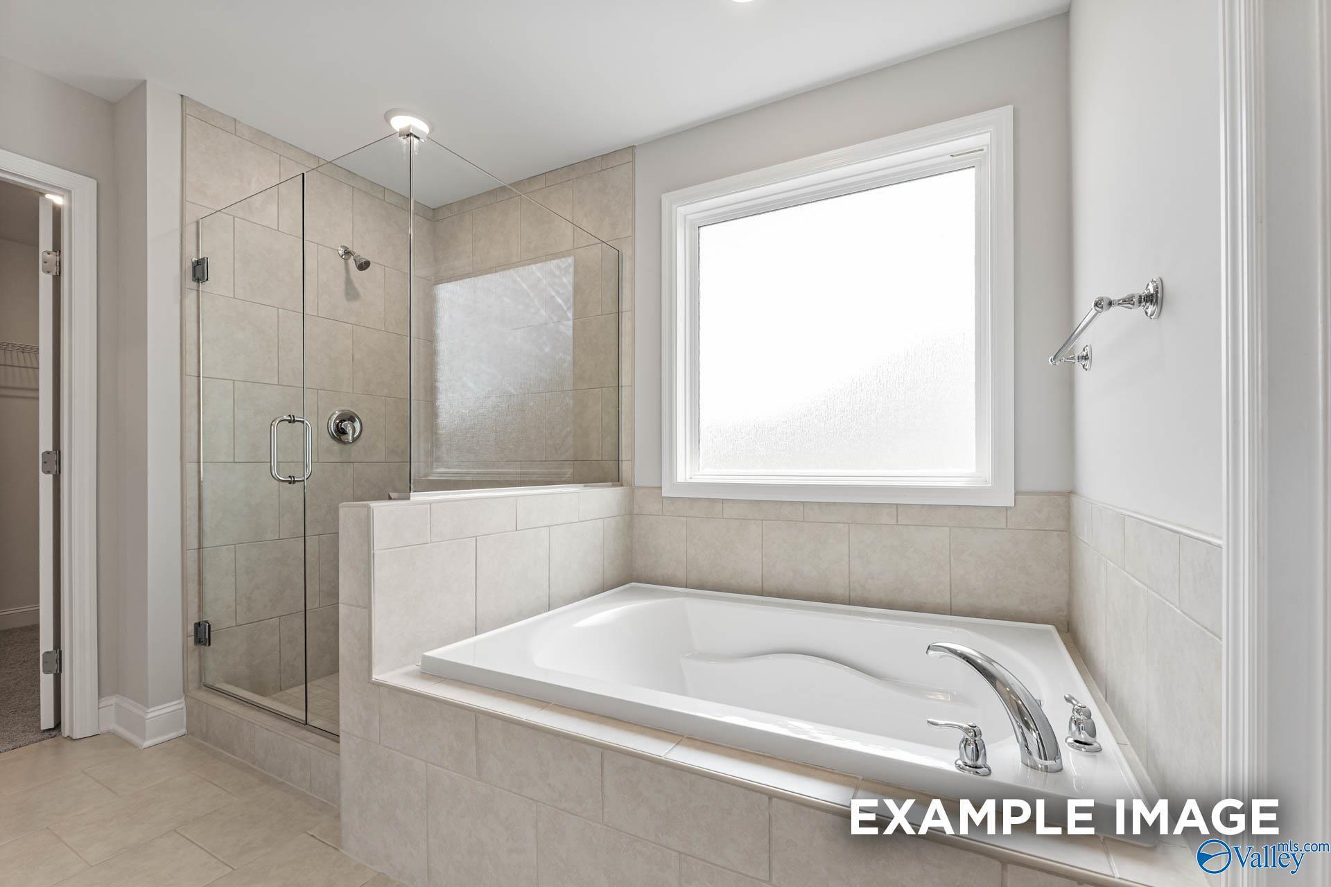 Modern bathroom with glass-enclosed shower and soaking tub in The Madison A floor plan by Davidson Homes in Athens, AL.