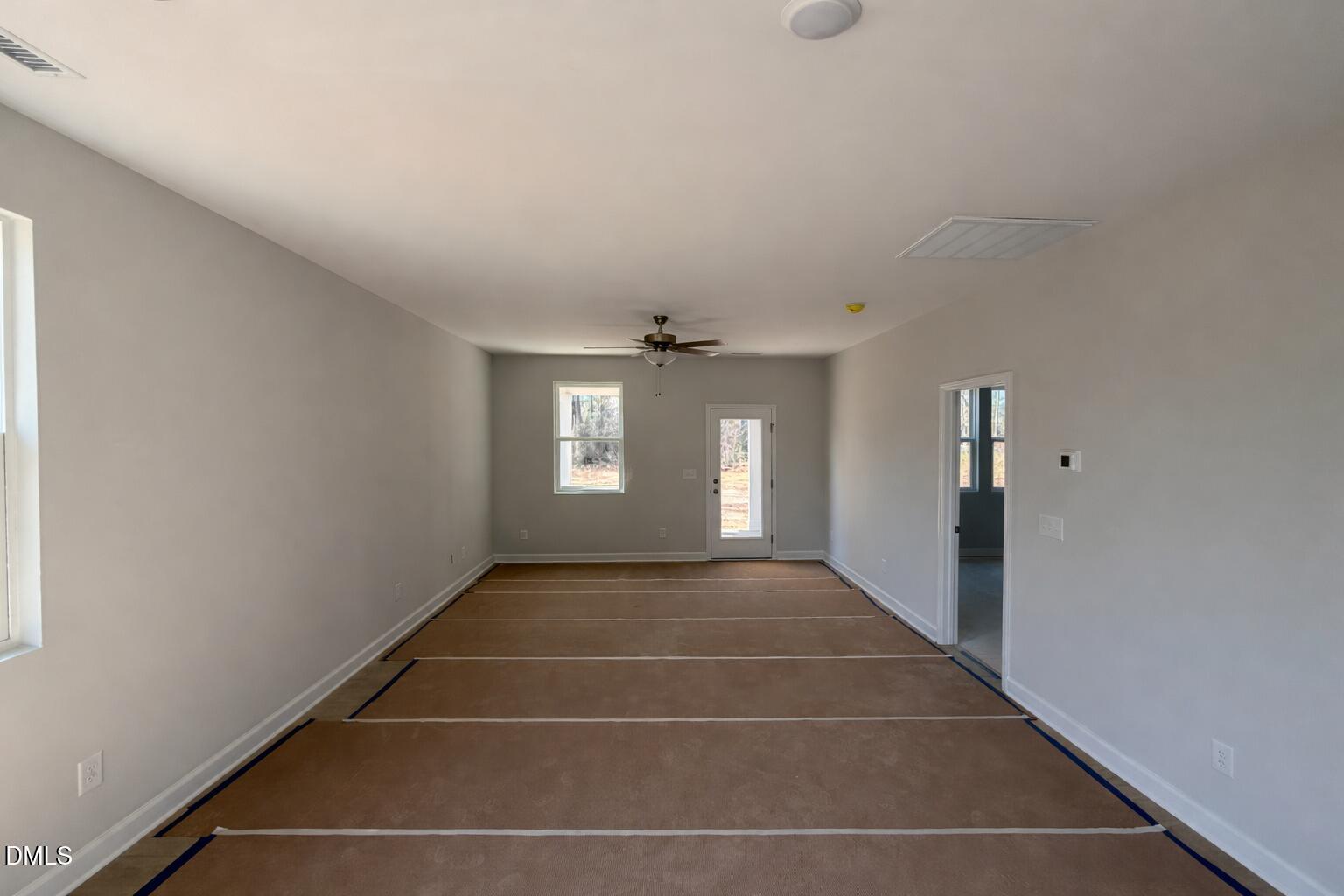 Spacious living area with plywood subflooring, ceiling fan, and glass patio door in The Carter C 3-bedroom home, Lillington, NC