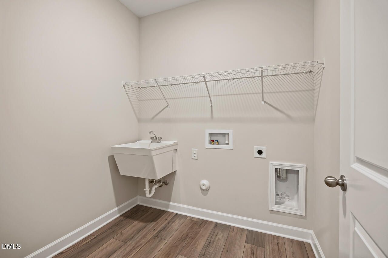 Laundry room with utility sink and wire shelving in The Ash C floor plan at Woodland Crossing, Zebulon, North Carolina.