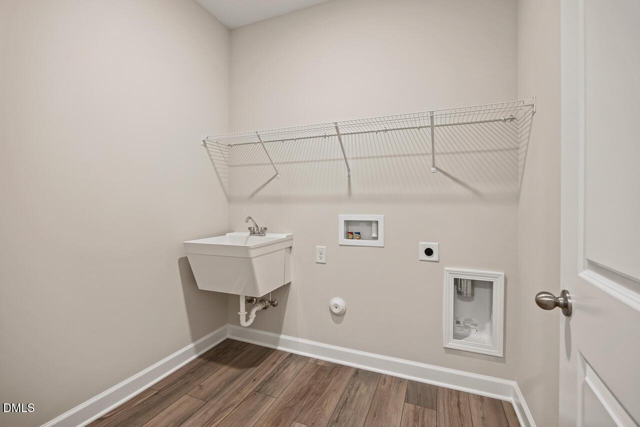 Laundry room with utility sink and wire shelving in The Ash C floor plan at Woodland Crossing, Zebulon, North Carolina.