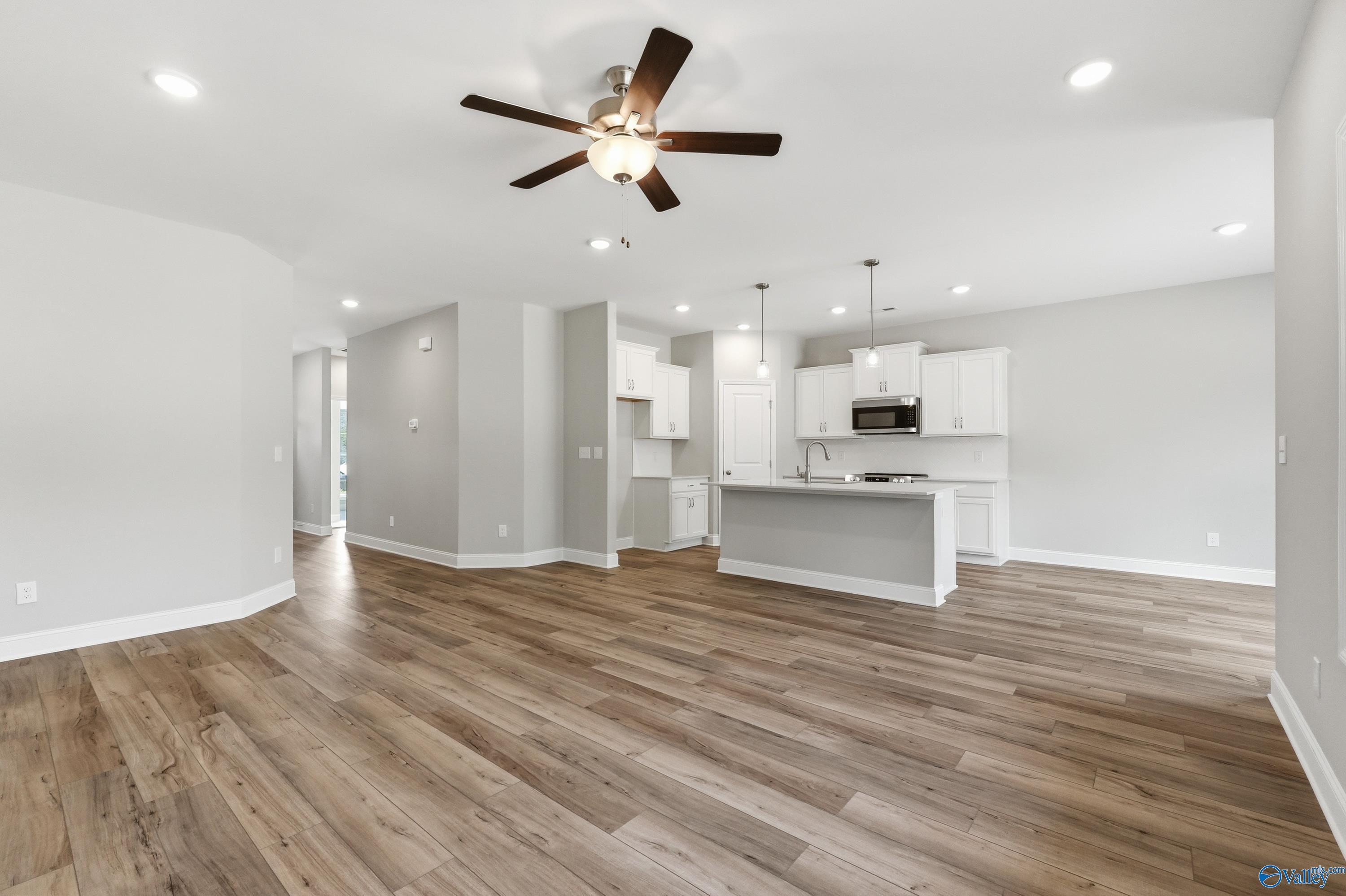 Modern open-concept kitchen with white cabinets, large center island cooktop, and hardwood floors in Davidson Homes The Asheville, Huntsville AL