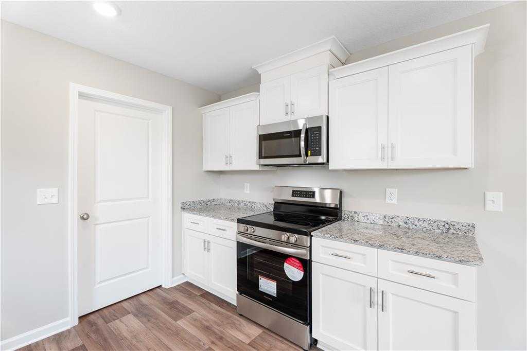Modern kitchen featuring white shaker cabinets, granite countertops, stainless steel appliances in Evermore Homes The Washington, Phenix City, Alabama