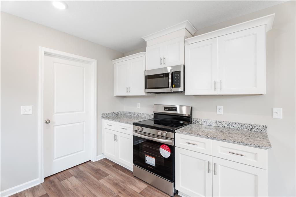 Modern kitchen featuring white shaker cabinets, granite countertops, stainless steel appliances in Evermore Homes The Washington, Phenix City, Alabama