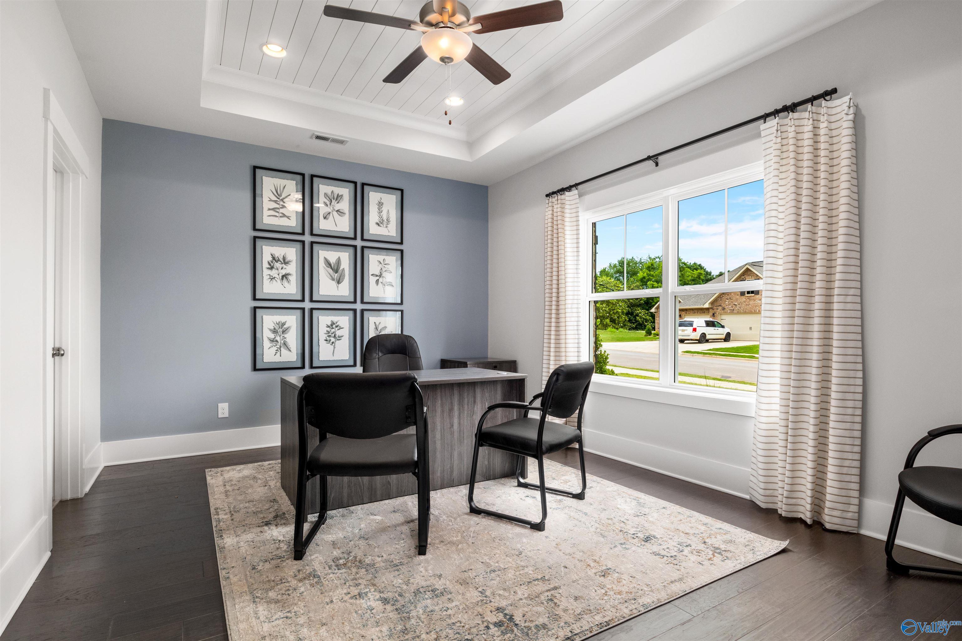 Cozy home office with gray walls, botanical art, desk, chairs, ceiling fan, and window view in Davidson Homes The Covington C, Decatur, AL