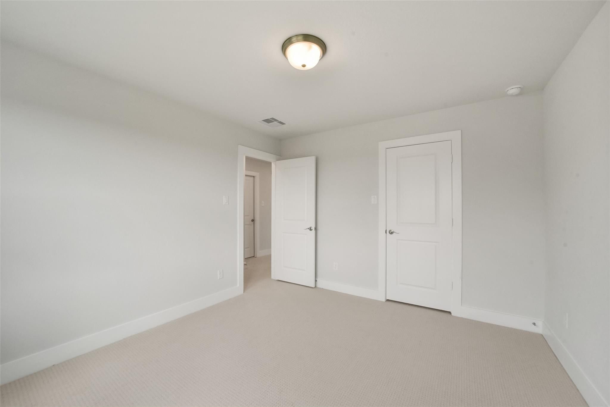 Bright secondary bedroom with neutral gray walls, white doors, carpet flooring in Davidson Homes The Zion A, Lago Mar, Texas City