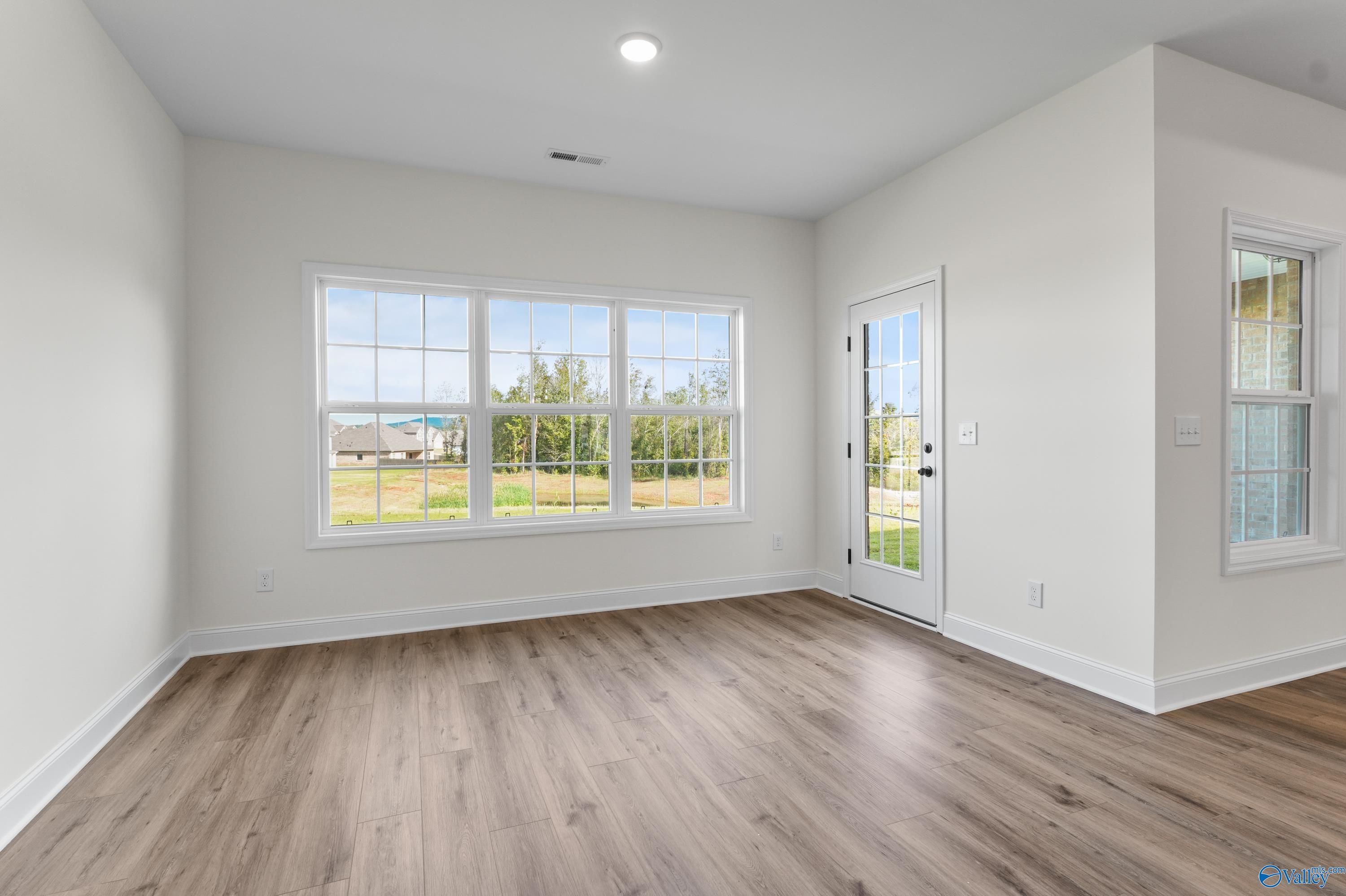 Bright living room with large windows and French door overlooking fields, hardwood floors in Davidson Homes The Finleigh, Harvest AL