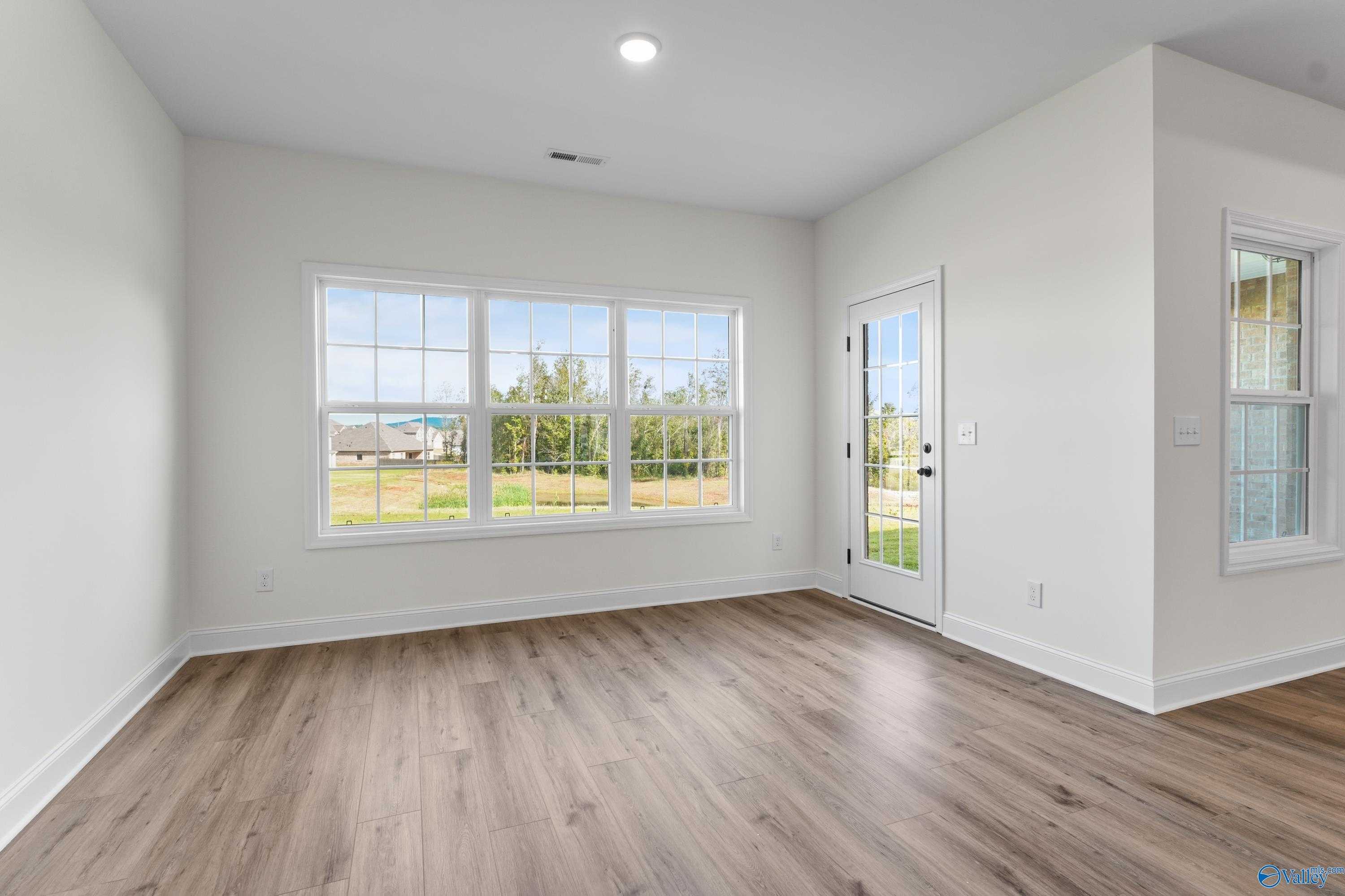 Bright living room with large windows and French door overlooking fields, hardwood floors in Davidson Homes The Finleigh, Harvest AL