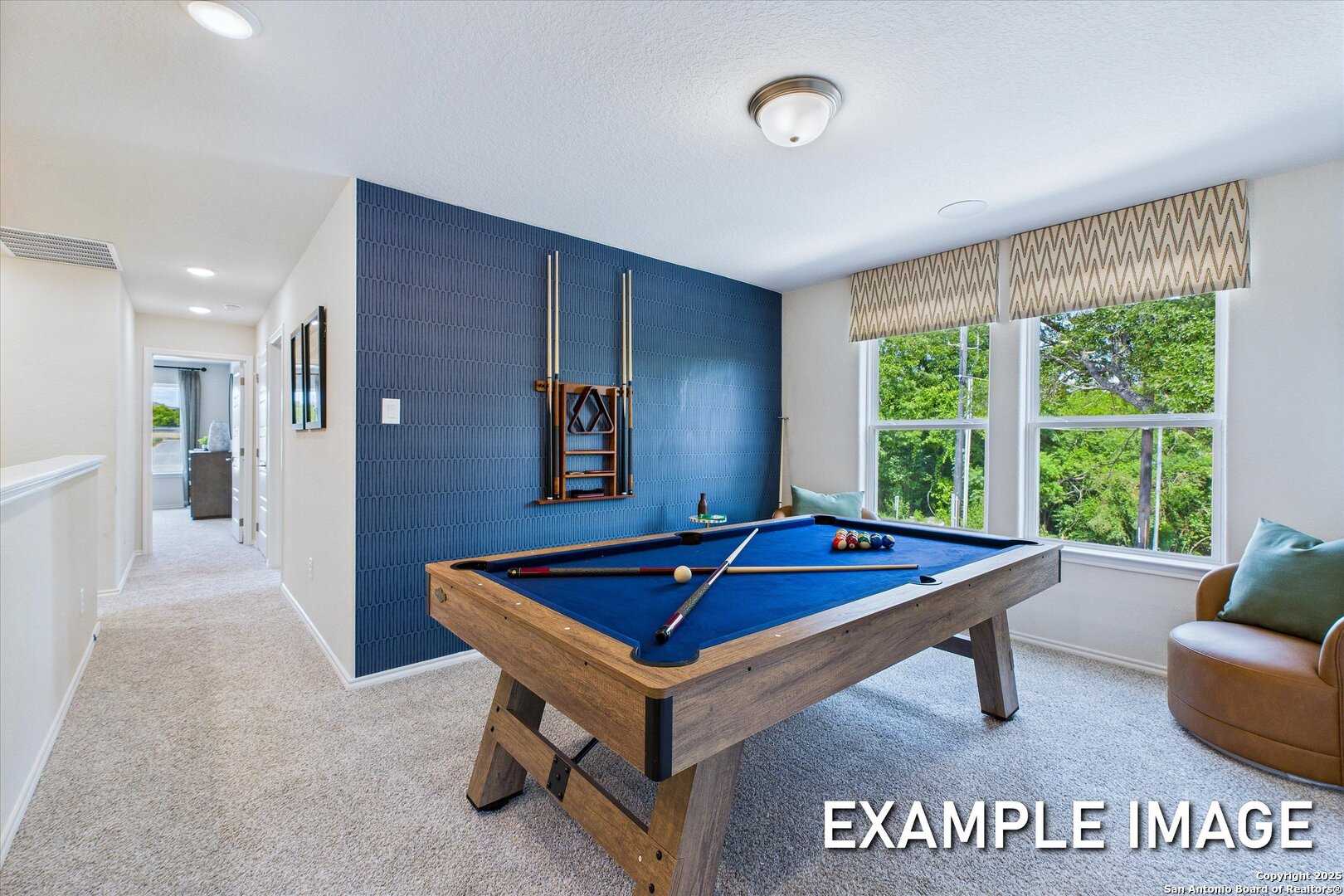 Game room with wooden billiards table, blue accent wall, and large windows in Davidson Homes The Gillian C, San Antonio, Texas