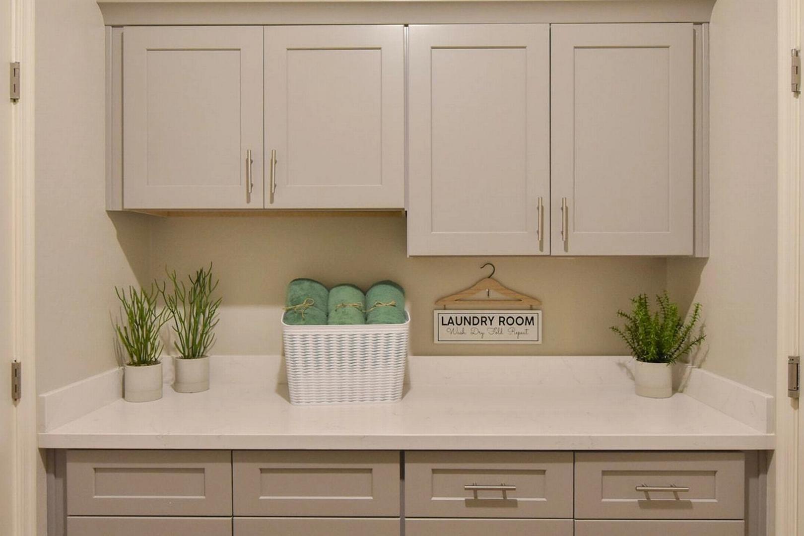 Spacious laundry room with shaker cabinets, quartz counters, towel basket and plants at North Ridge Pronghorn Ranch, Prescott Valley AZ