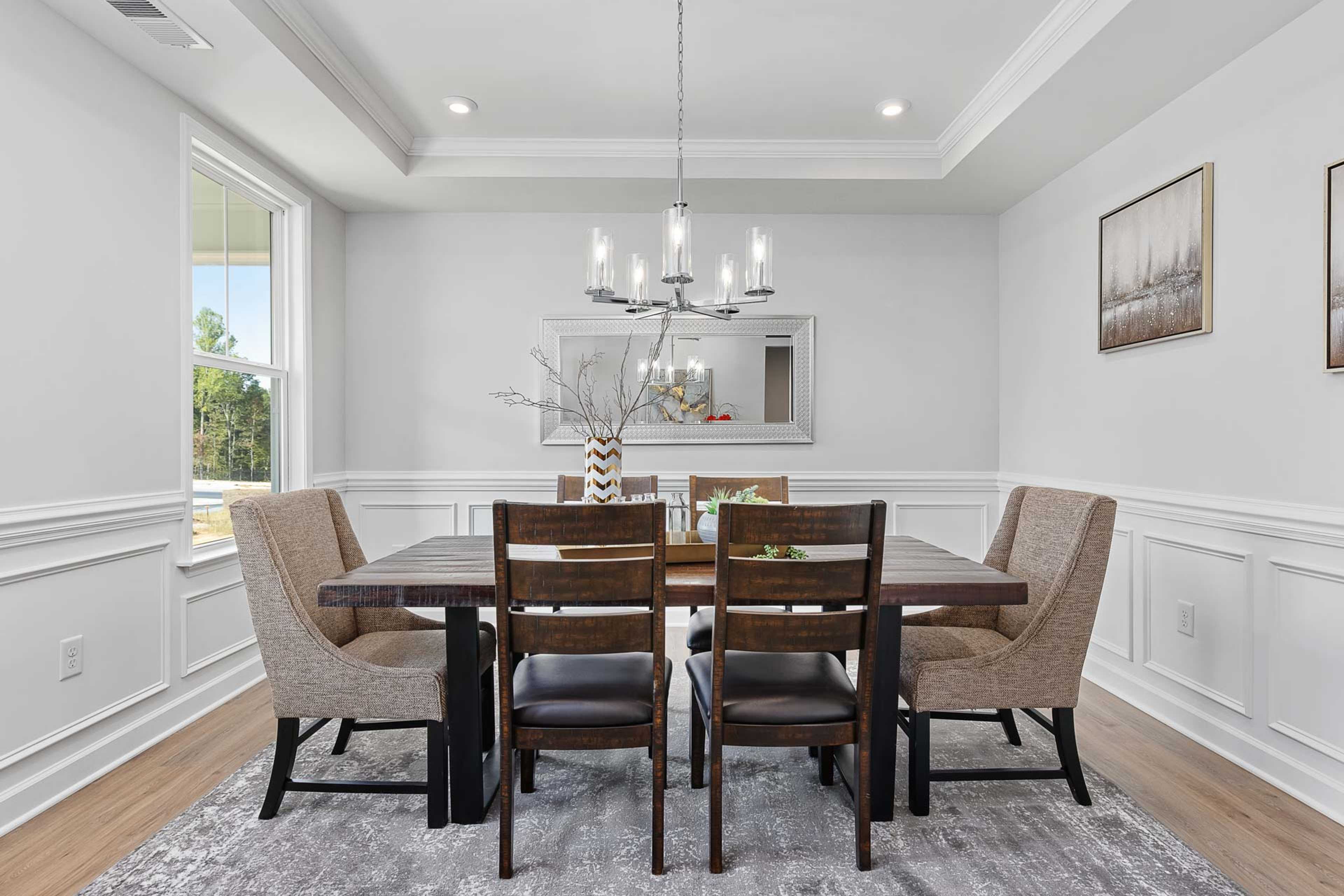 Elegant dining room in Glenmere, Knightdale NC with wooden table, upholstered chairs, chandelier, and large window