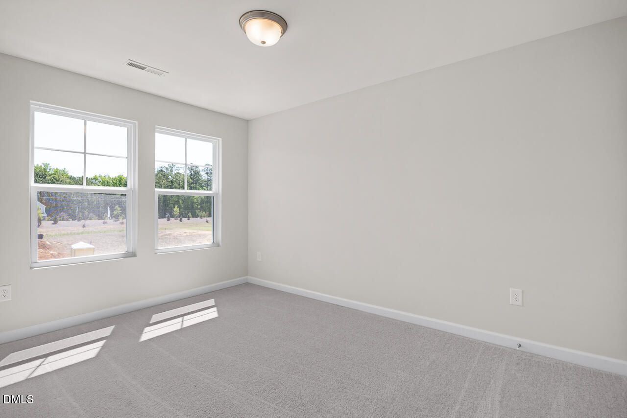 Bright, spacious bedroom with neutral carpet and natural light in The Grace C floor plan, Retreat at North Main, Lillington.
