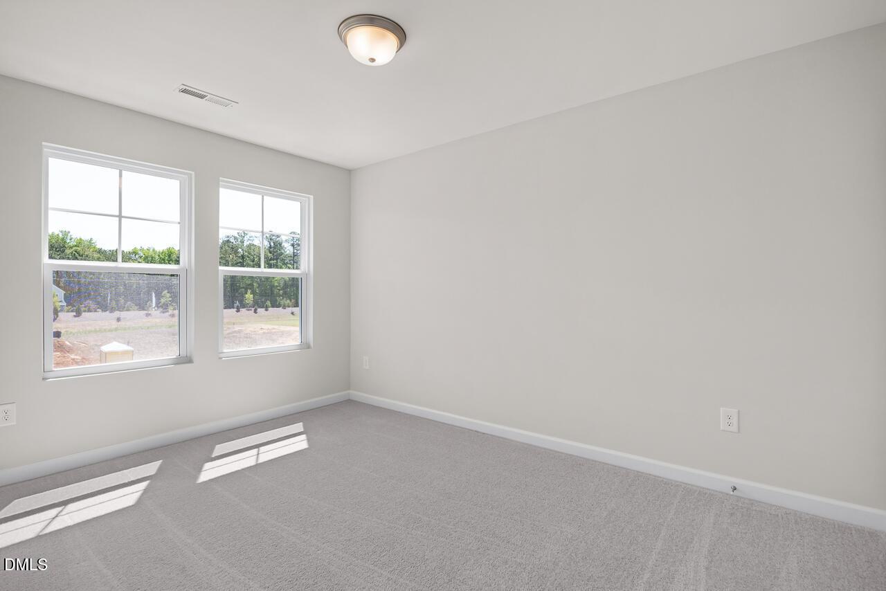 Bright, spacious bedroom with neutral carpet and natural light in The Grace C floor plan, Retreat at North Main, Lillington.
