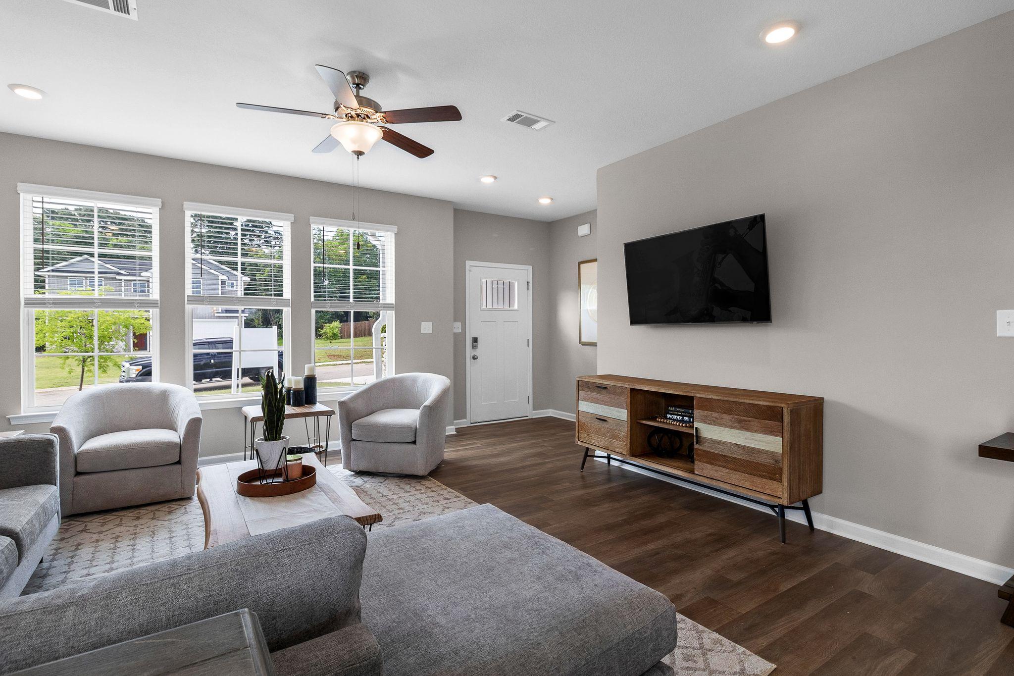 Spacious open-concept living room in Ivy Glen Perry Georgia with hardwood floors gray sectional sofa large windows and ceiling fan
