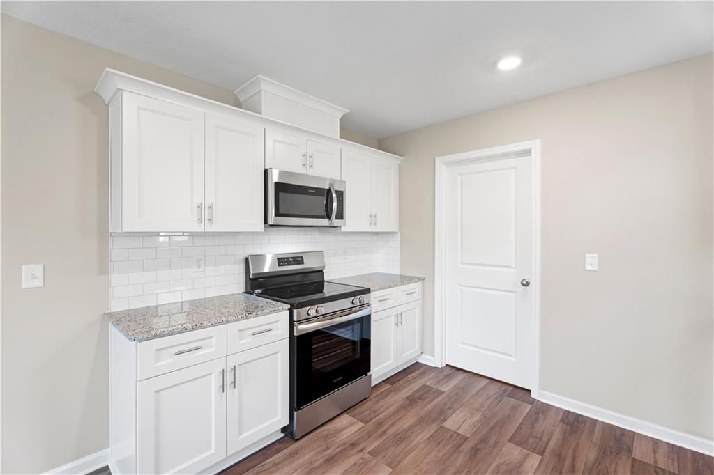 Modern white kitchen with granite countertops, stainless appliances, subway tile backsplash in Davidson Homes The Washington, Phenix City