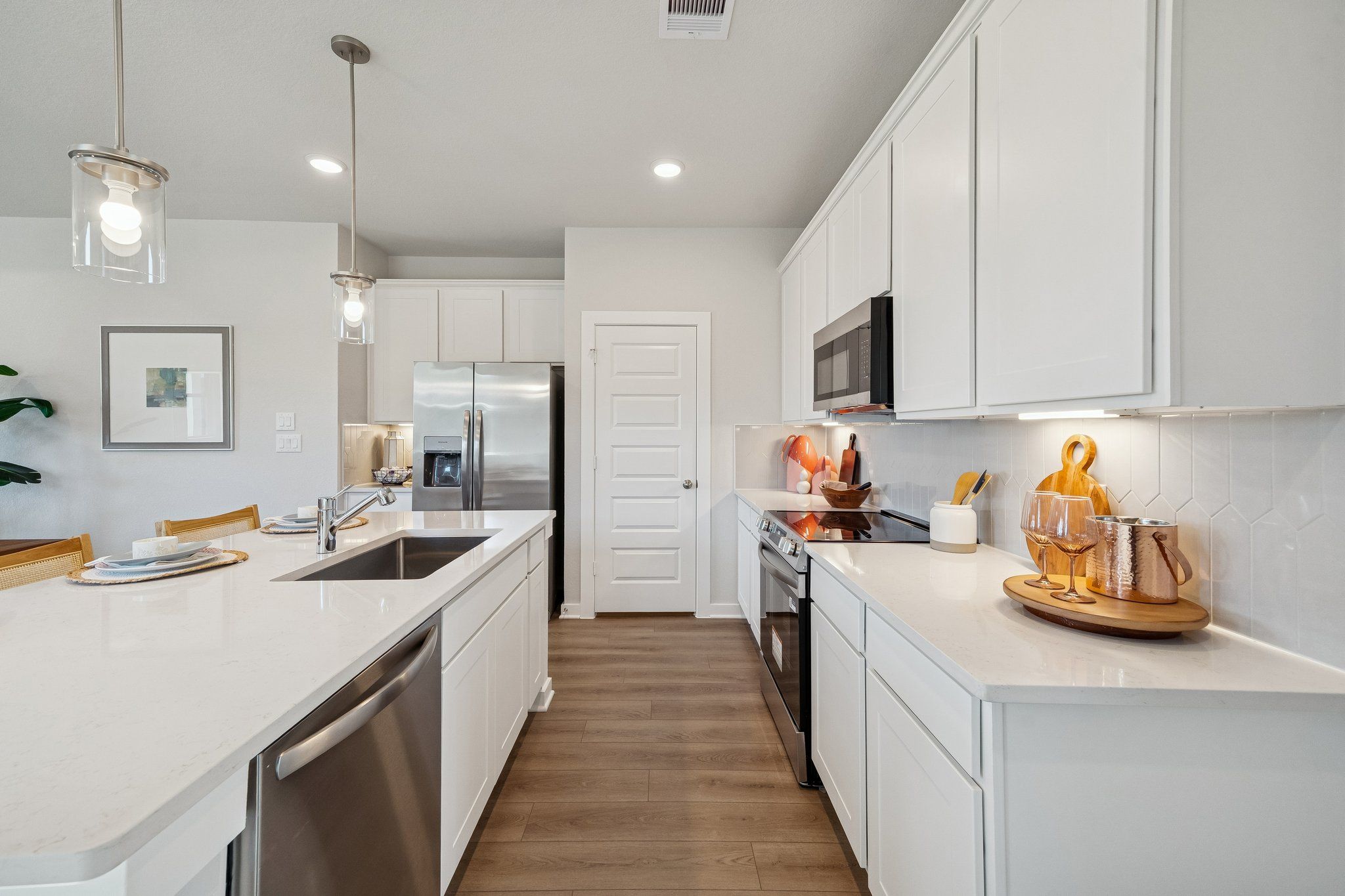Spacious modern kitchen at Spring Branch Crossing in Conroe TX with white shaker cabinets, quartz island, stainless appliances