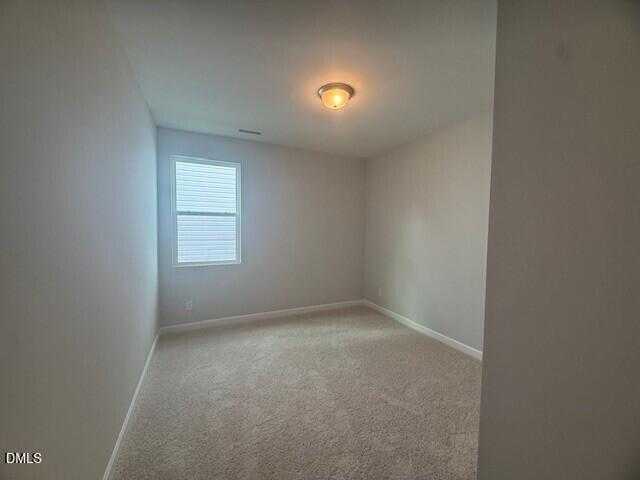 Bright empty bedroom with beige walls, carpet floor, and double window in The Preston C 4-bedroom home, Lillington, NC