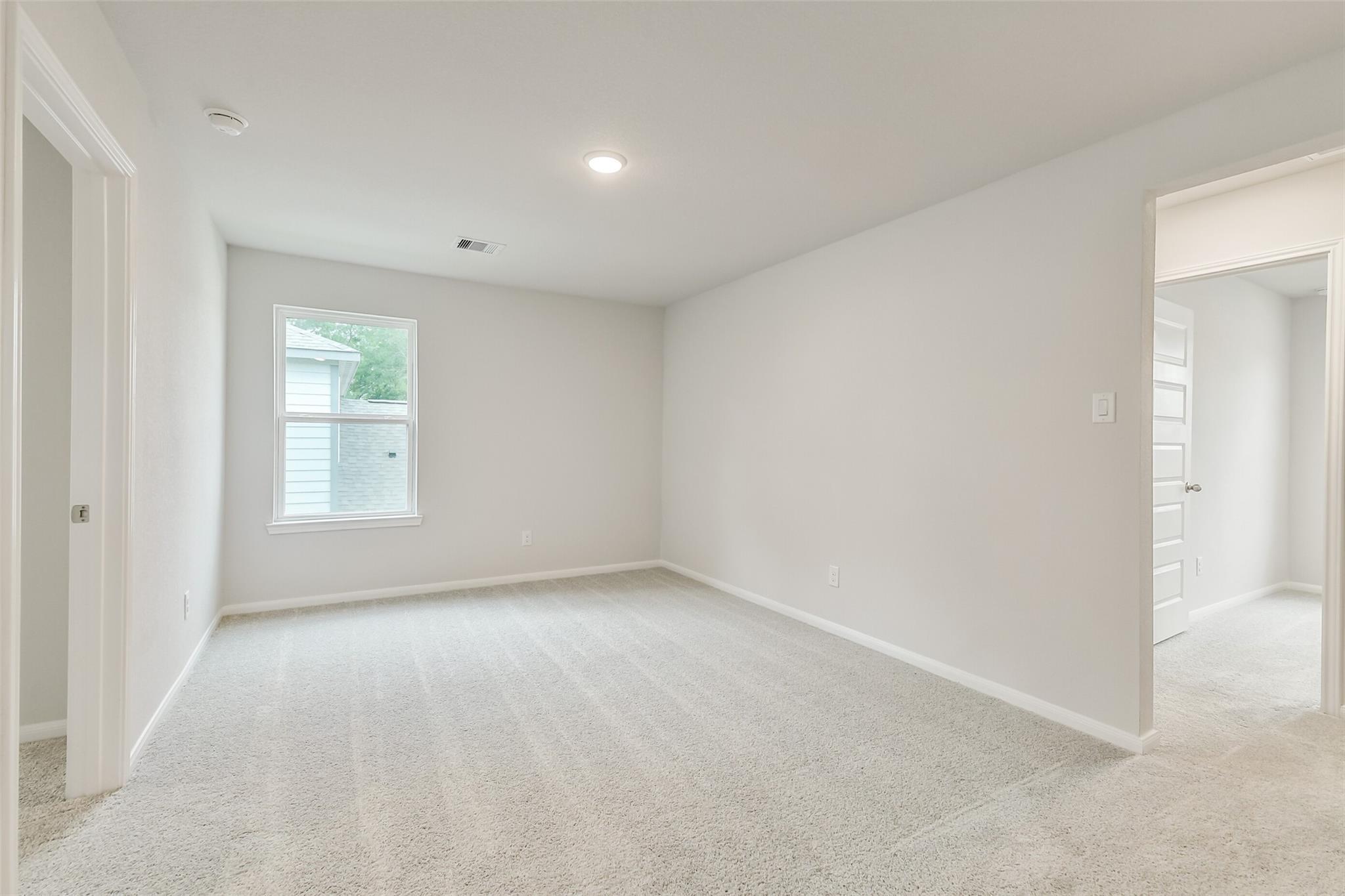Bright secondary bedroom with neutral walls, carpet flooring, and window in Davidson Homes The Brazos F, Conroe, Texas