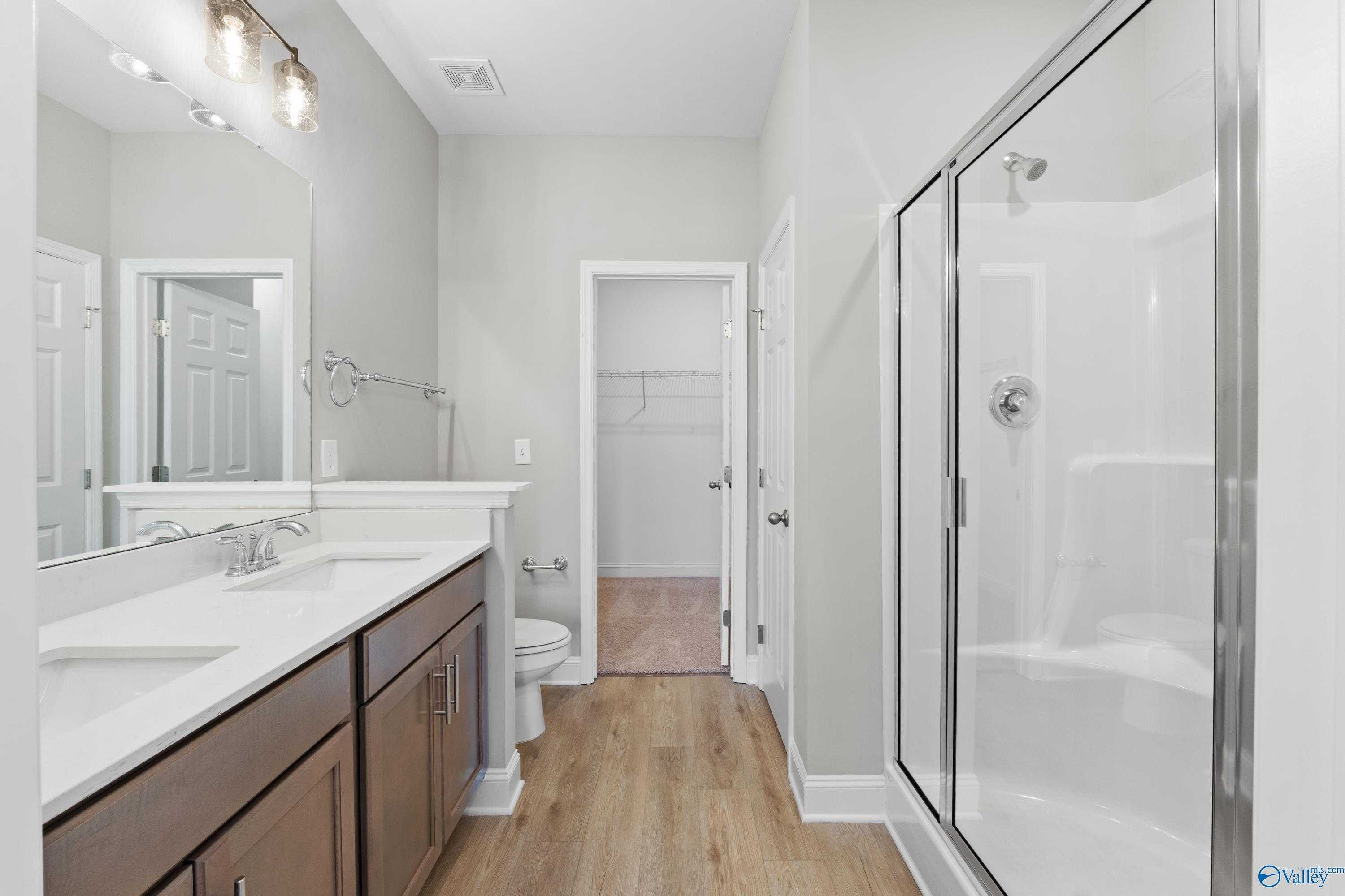 Modern master bathroom featuring double vanity, frameless glass shower, and walk-in closet in Davidson Homes The Asheville C, Athens AL