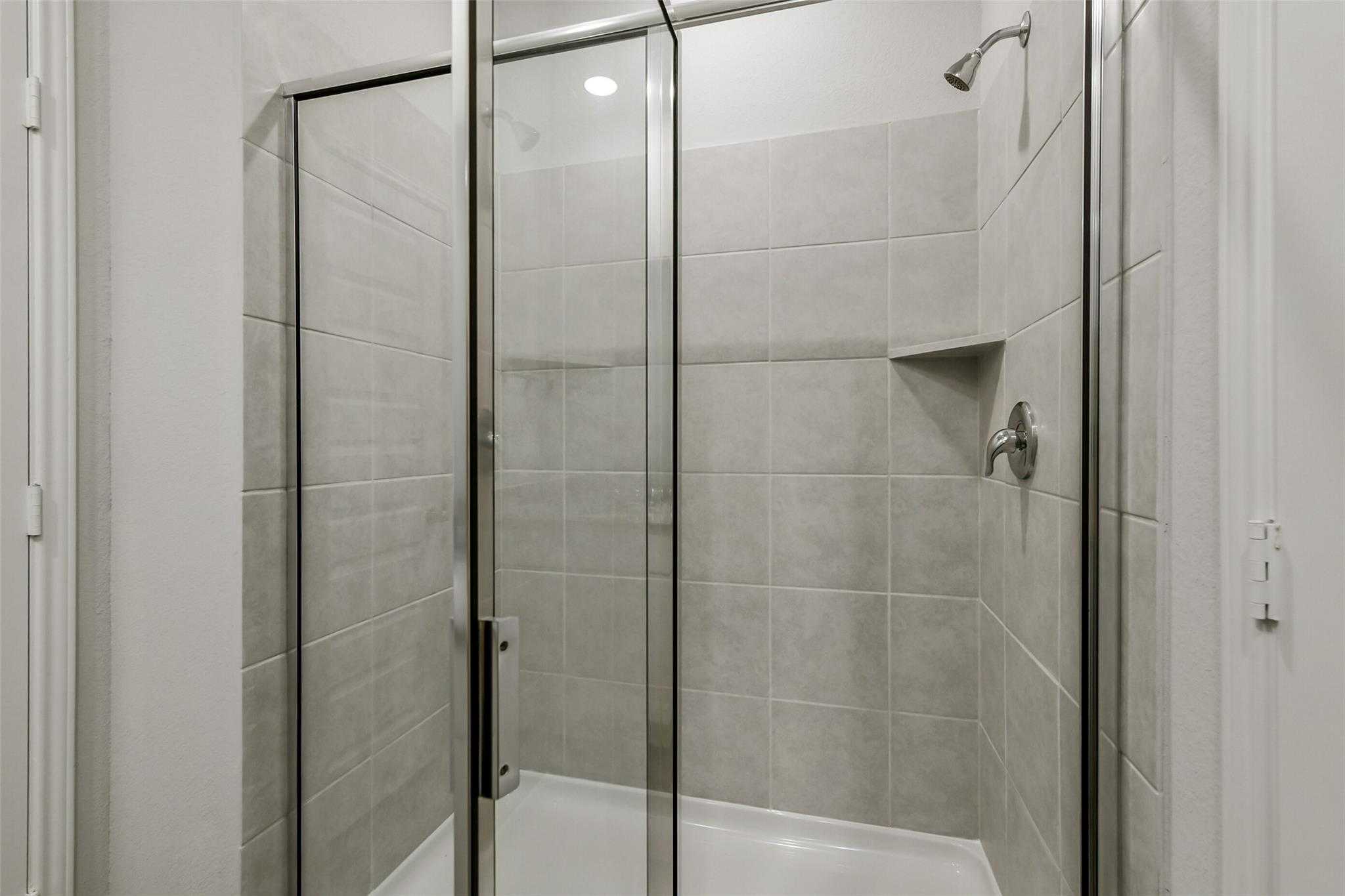 Frameless glass walk-in shower with subway tile walls, rain showerhead, and niche in master bath, The Sabine E, Conroe Texas