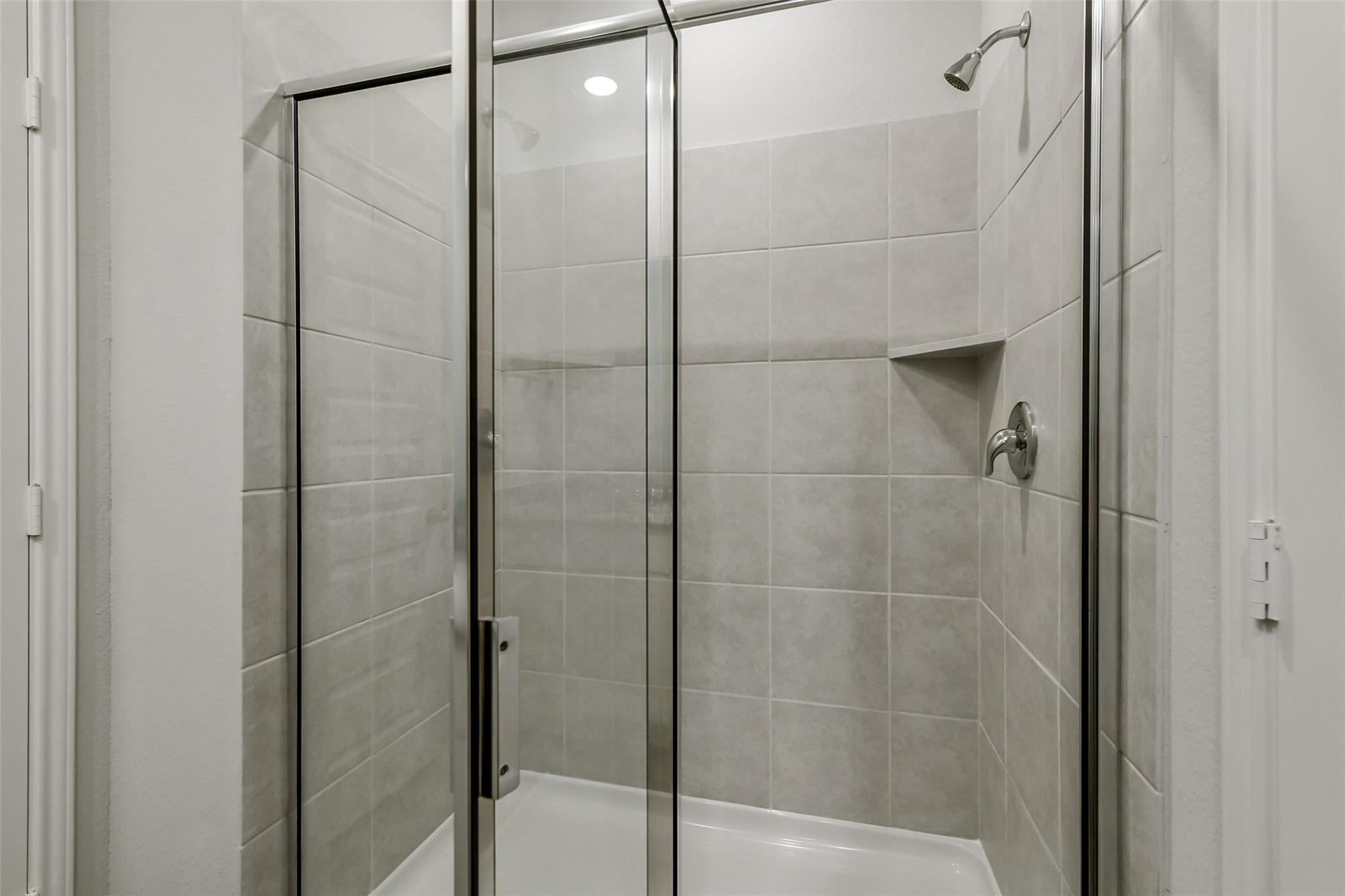 Frameless glass walk-in shower with subway tile walls, rain showerhead, and niche in master bath, The Sabine E, Conroe Texas