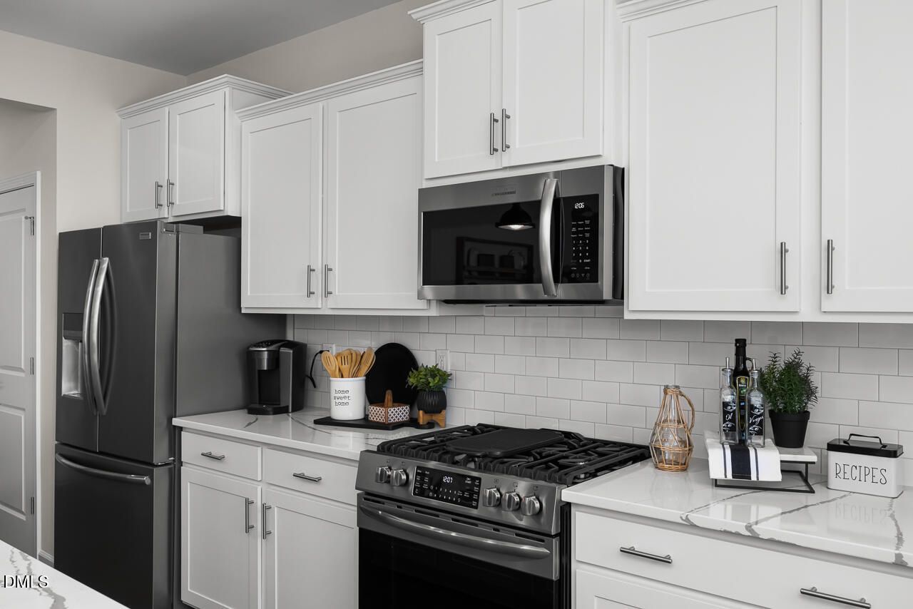 Modern kitchen with white cabinets, stainless steel appliances, subway tile backsplash in 5-bed Hickory II B home, Zebulon NC