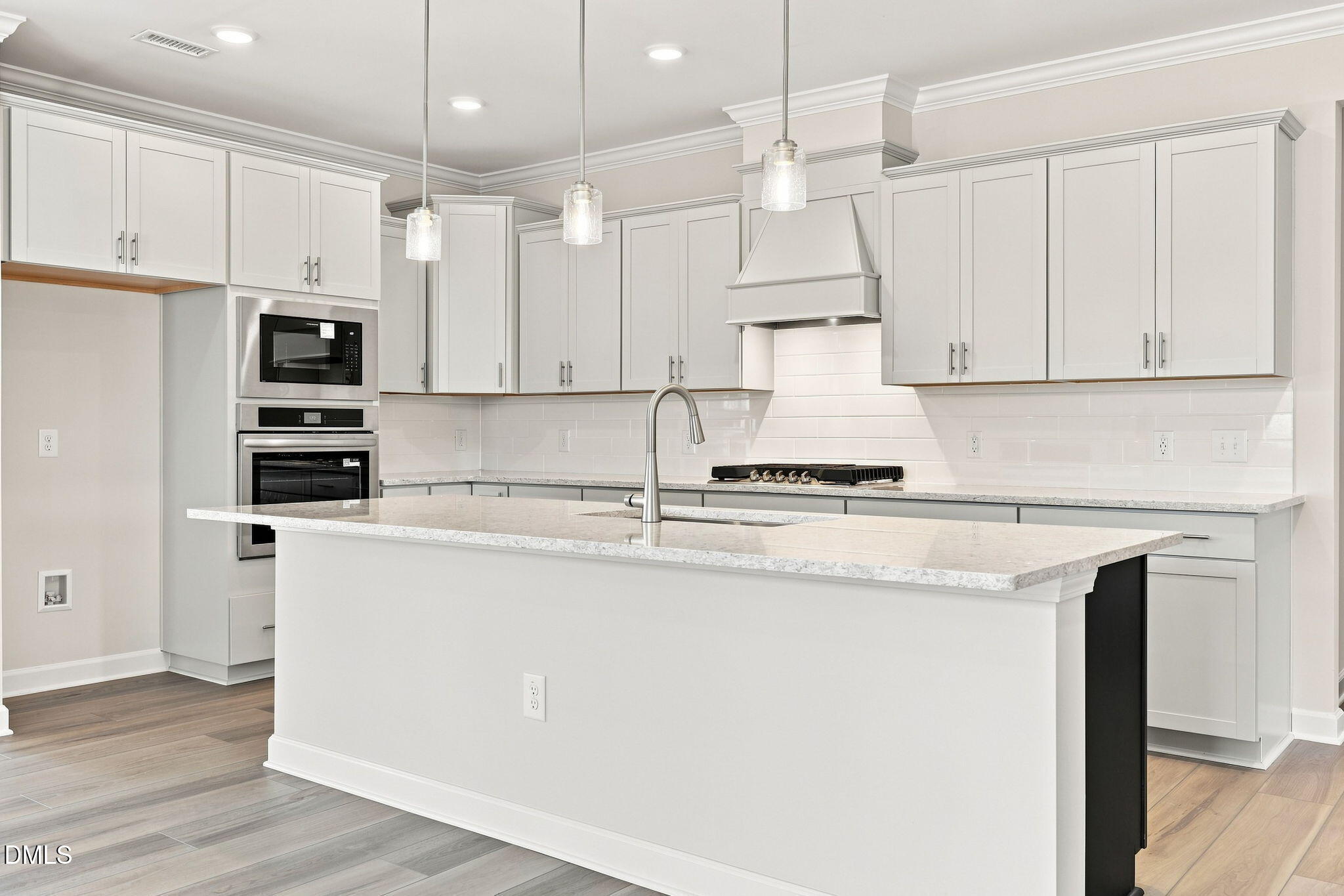 Modern kitchen with white cabinets, granite island, and pendant lighting in The Magnolia B at Retreat at North Main, Lillington