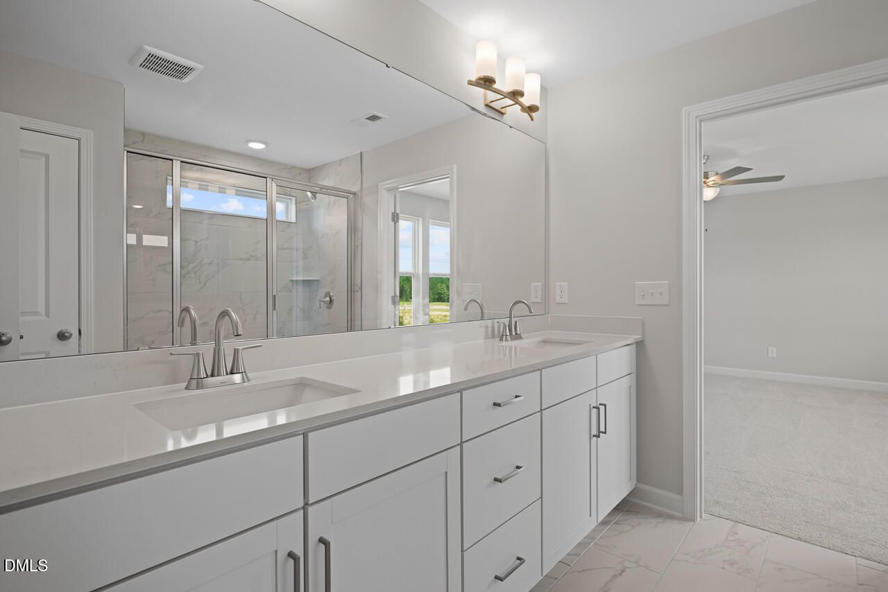 Modern primary bathroom with double vanity and glass-enclosed shower in The Chestnut floor plan at Wendell Ridge, NC.