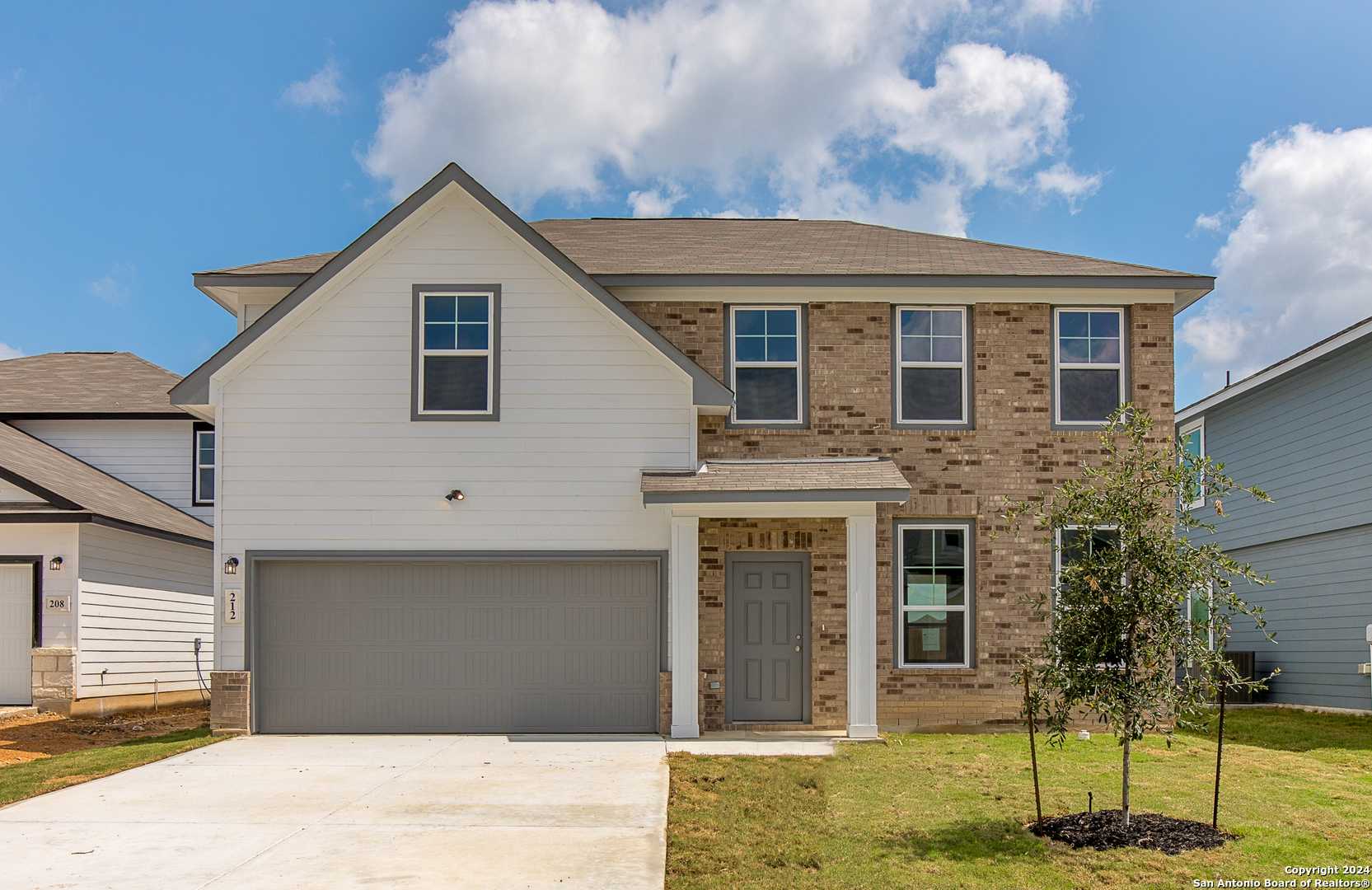 Modern two-story 4-bedroom home with brick accents, white siding, 2-car garage, and front porch in Hannah Heights, Seguin, Texas