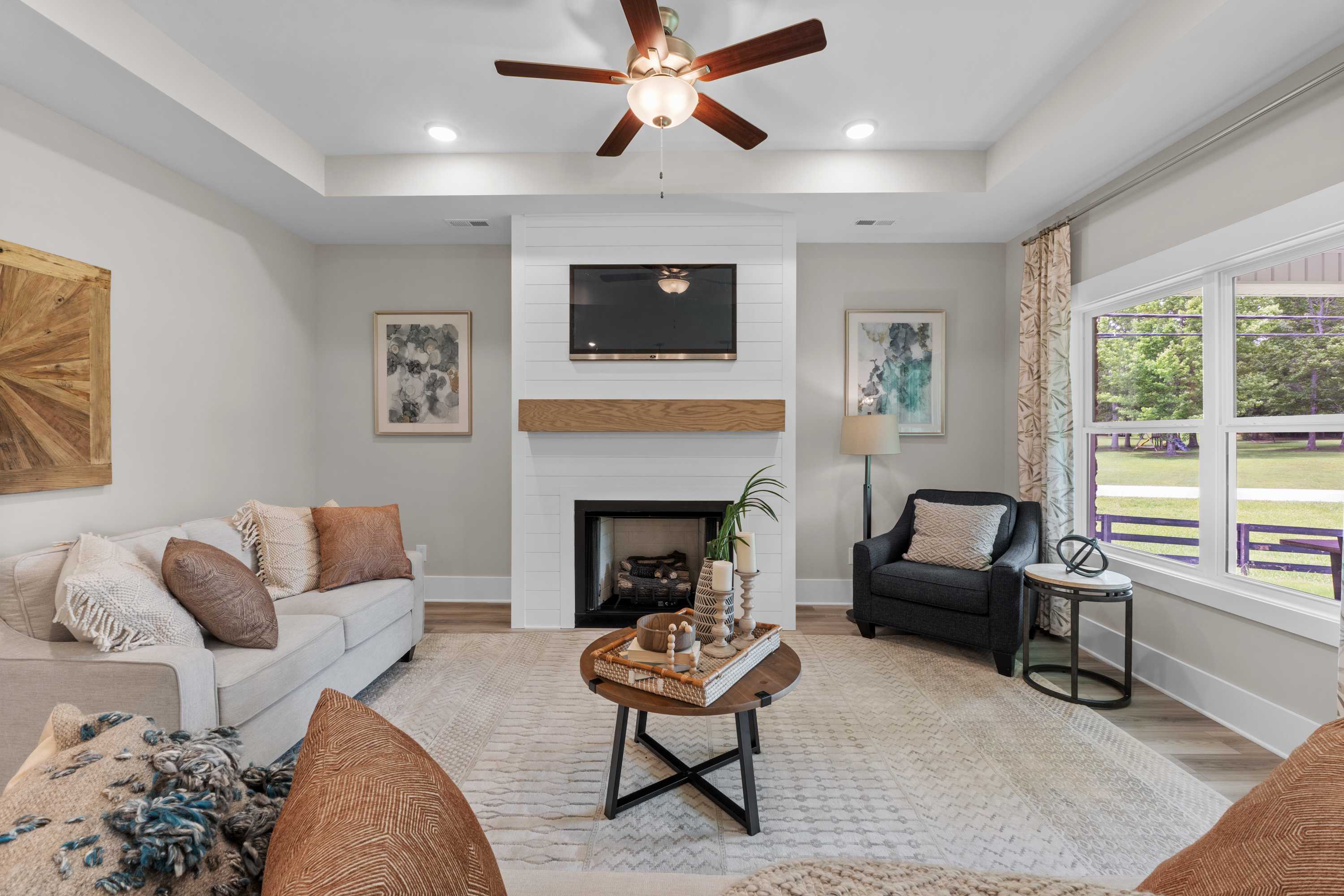 Cozy living room at The Highlands in Arab Alabama with shiplap fireplace TV ceiling fan hardwood floors and large windows