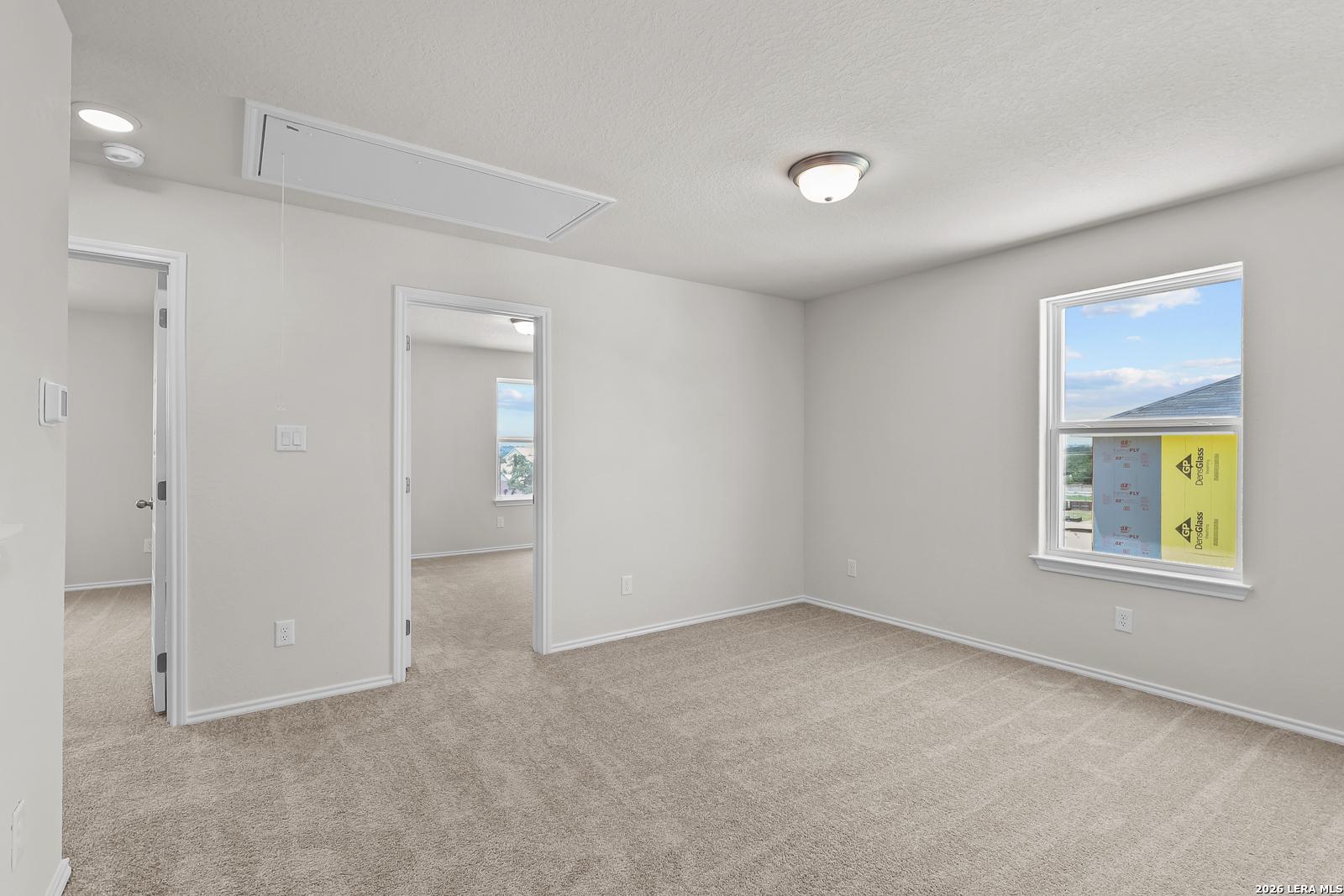 Bright secondary bedroom with plush carpeting in The Gillian B floor plan at Meadows at Oak Creek, San Antonio, Texas.