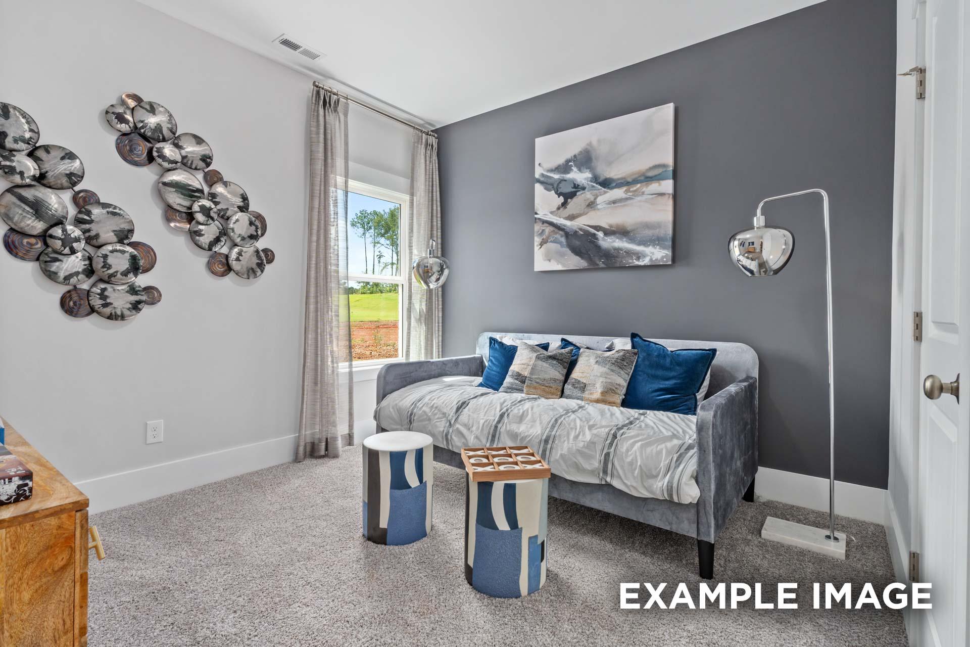 Cozy gray bedroom in The Franklin C by Davidson Homes featuring tufted daybed with blue pillows, abstract wall art, and window to green field