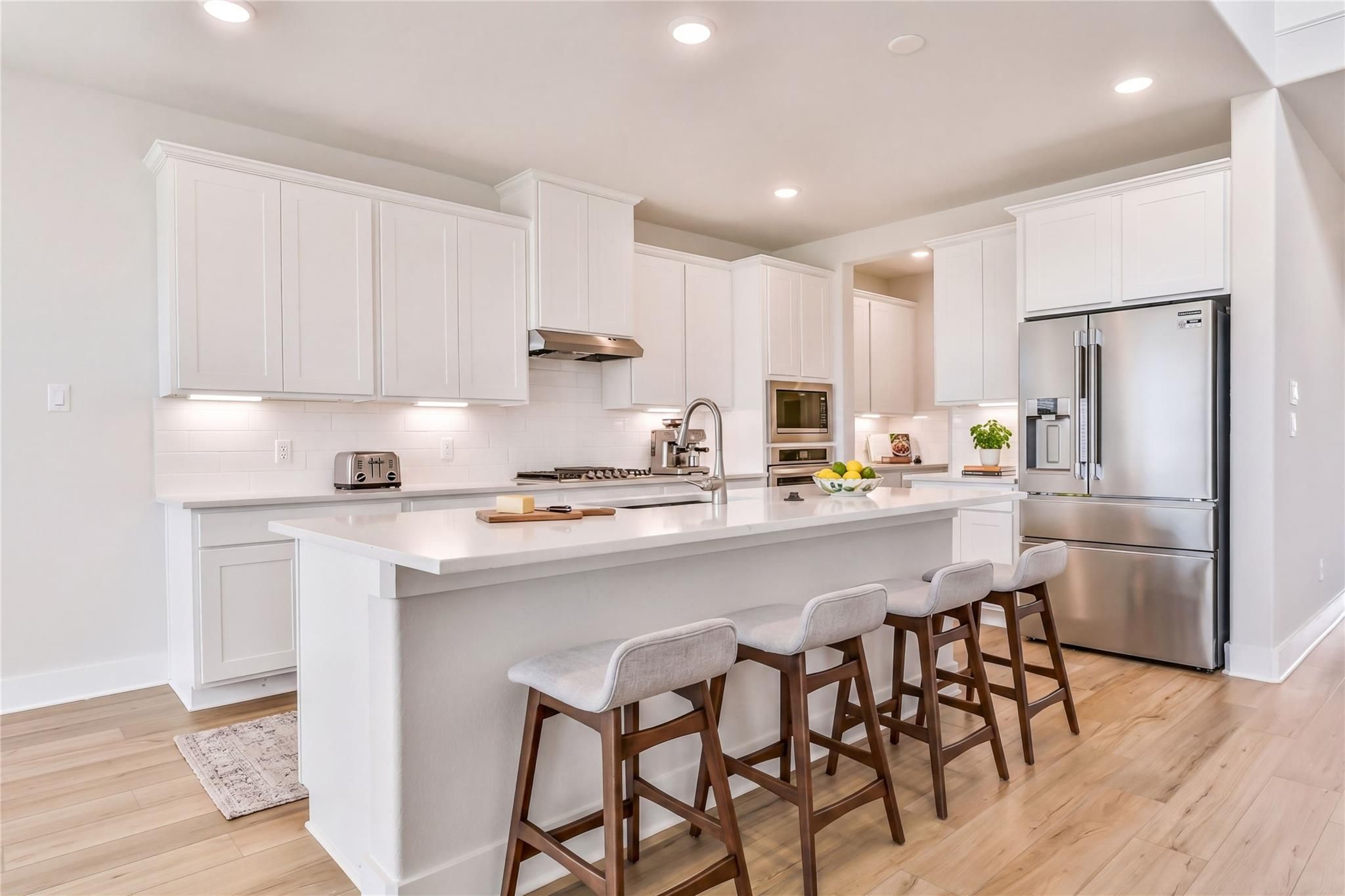 Modern white shaker kitchen with quartz island, stainless steel appliances, subway tile backsplash in Davidson Homes The Victoria A, Lago Mar Texas City