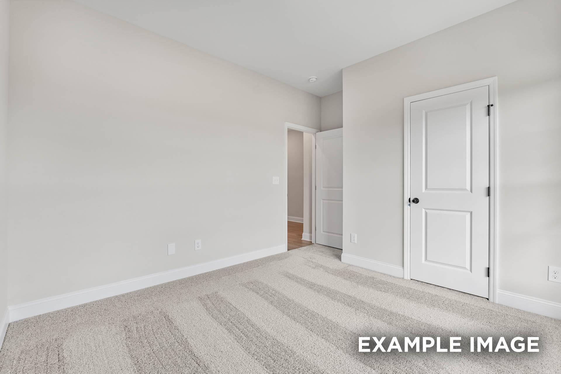 Spacious secondary bedroom with neutral carpet and white doors in The Franklin E floor plan at Bailey Park, Fayetteville.
