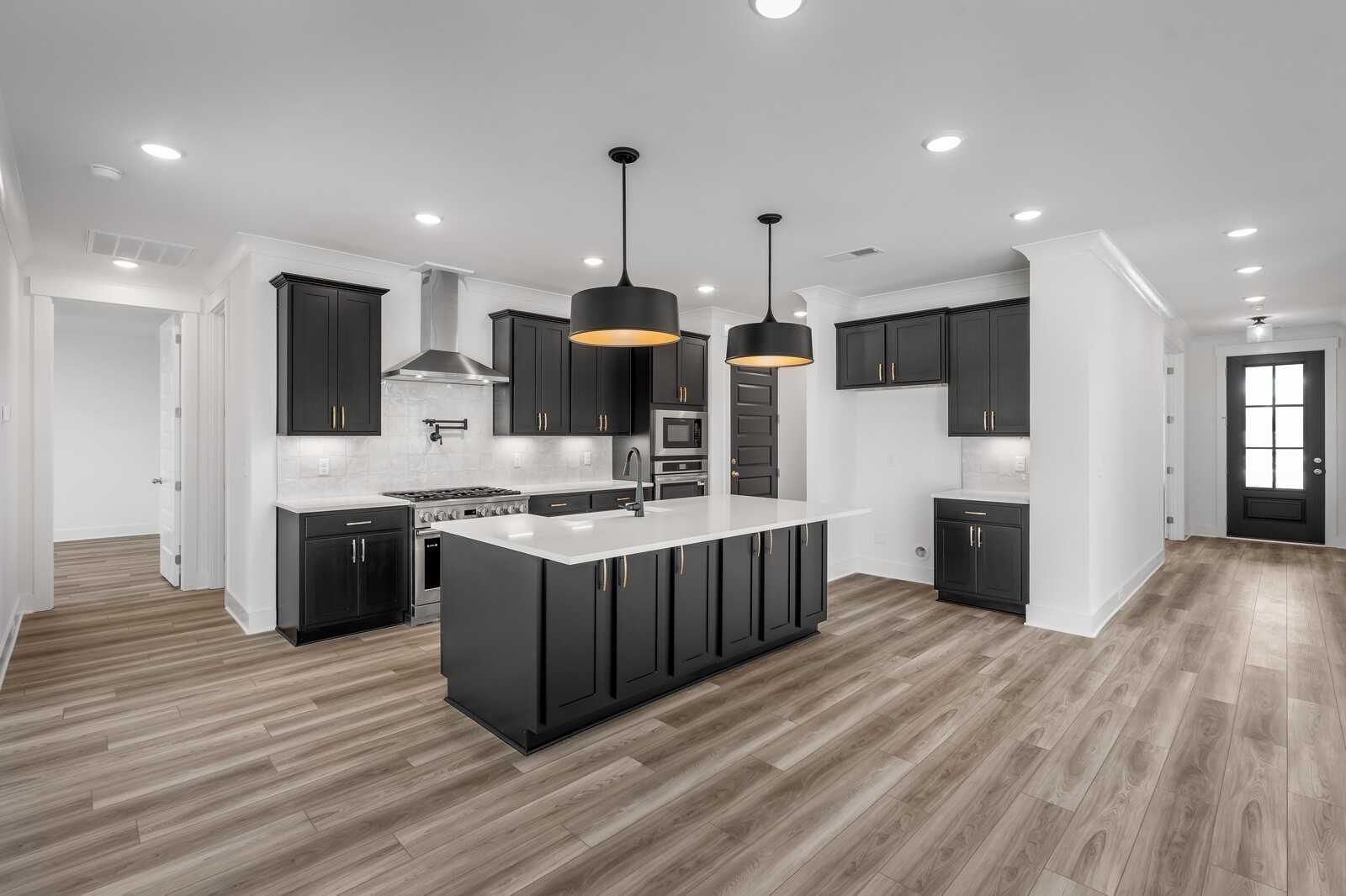 Modern open-concept kitchen with black cabinets, white quartz island, and pendant lights in Davidson Homes The Hathaway, Murfreesboro, TN