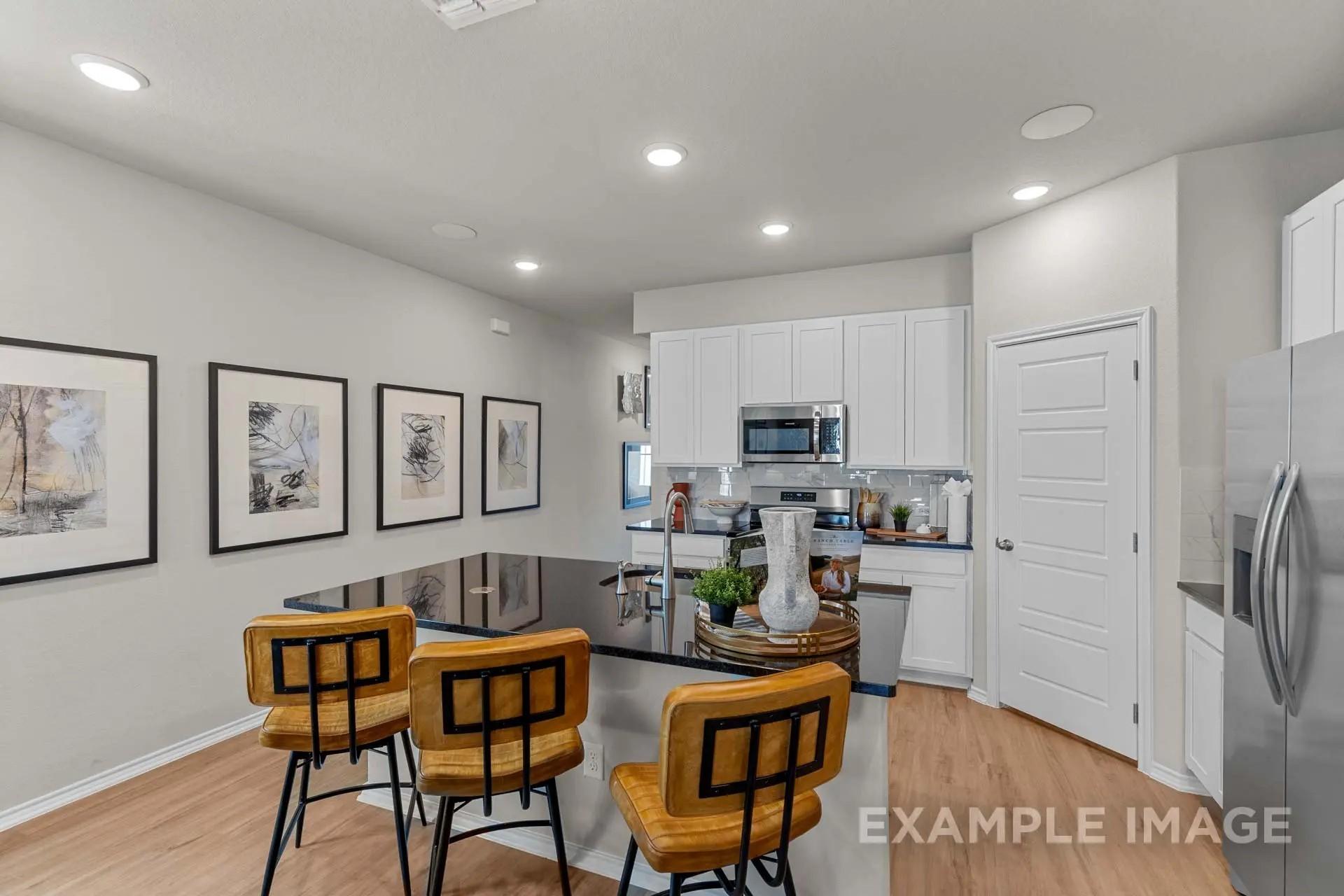 Modern kitchen with black island, white cabinets, and leather bar stools in The Sabine H floor plan in Heartland, Texas.
