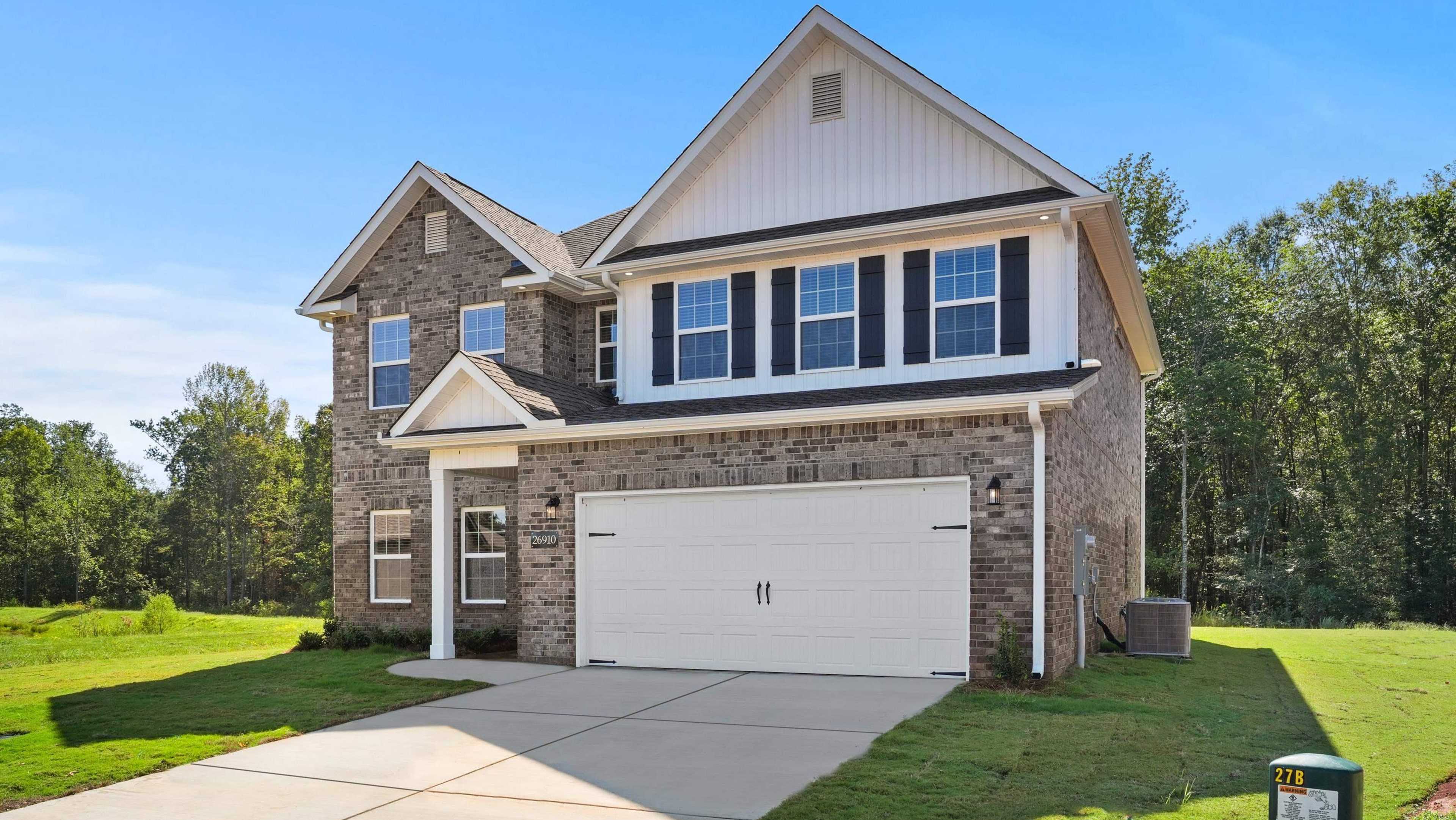 Modern two-story brick home with white trim, two-car garage, and manicured lawn at Davidson Homes open house on Kyle Lane