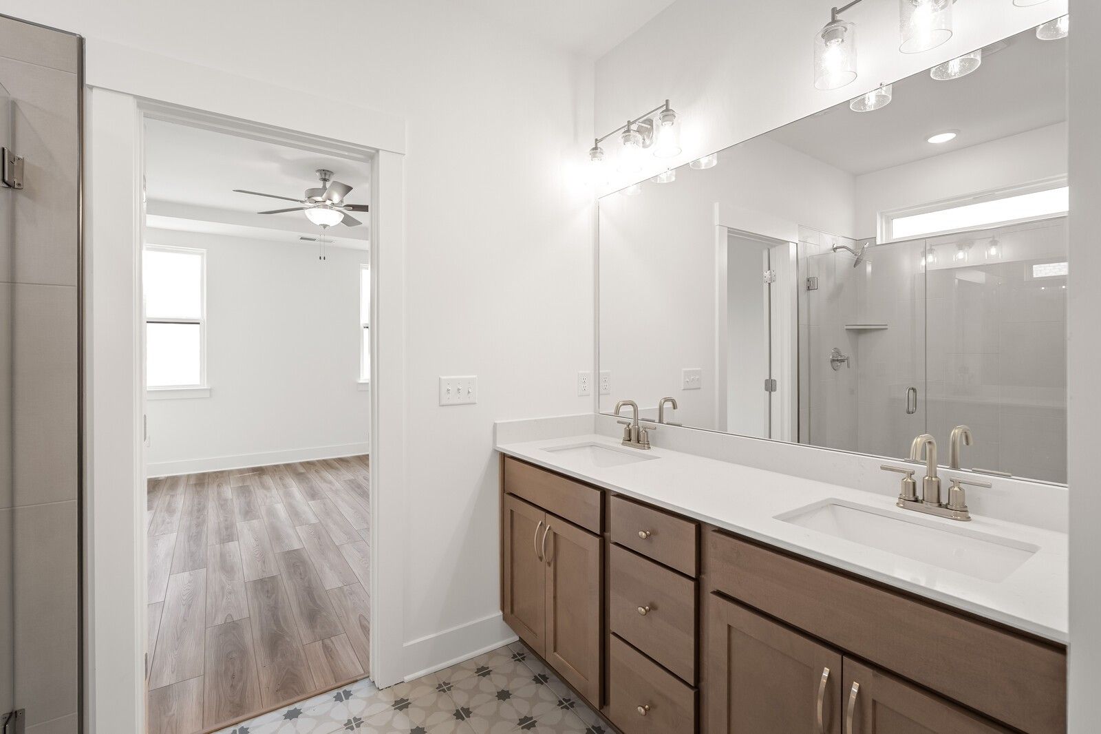 Elegant master bathroom with double sink vanity, frameless glass shower, and adjacent bedroom in Davidson Homes The Ash C, Mt. Juliet, TN