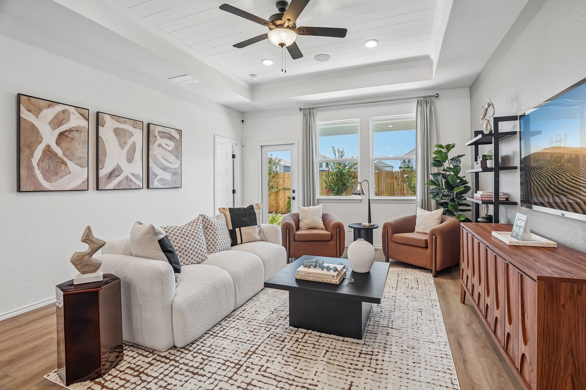 Modern living room at Fairway Crossing in Converse, TX, featuring a tray ceiling, plush sofa, and contemporary decor.