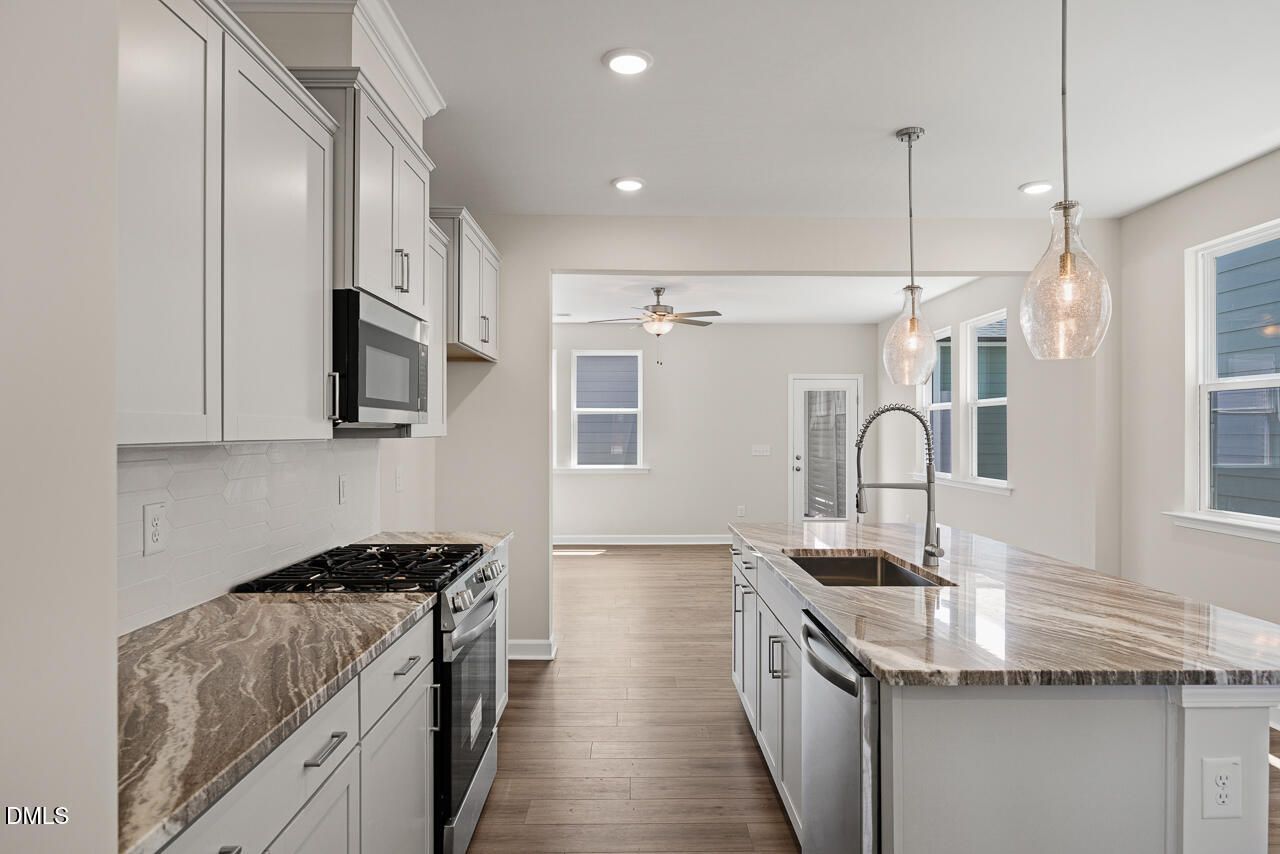 Modern kitchen with granite island and white cabinets in The Alexander C floor plan, Forestville Yard, Knightdale, NC.
