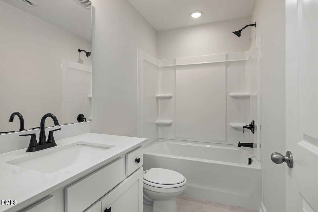 Modern bathroom with white vanity, quartz countertop, and tub-shower combo in Sage on North Main, Wake Forest, NC.